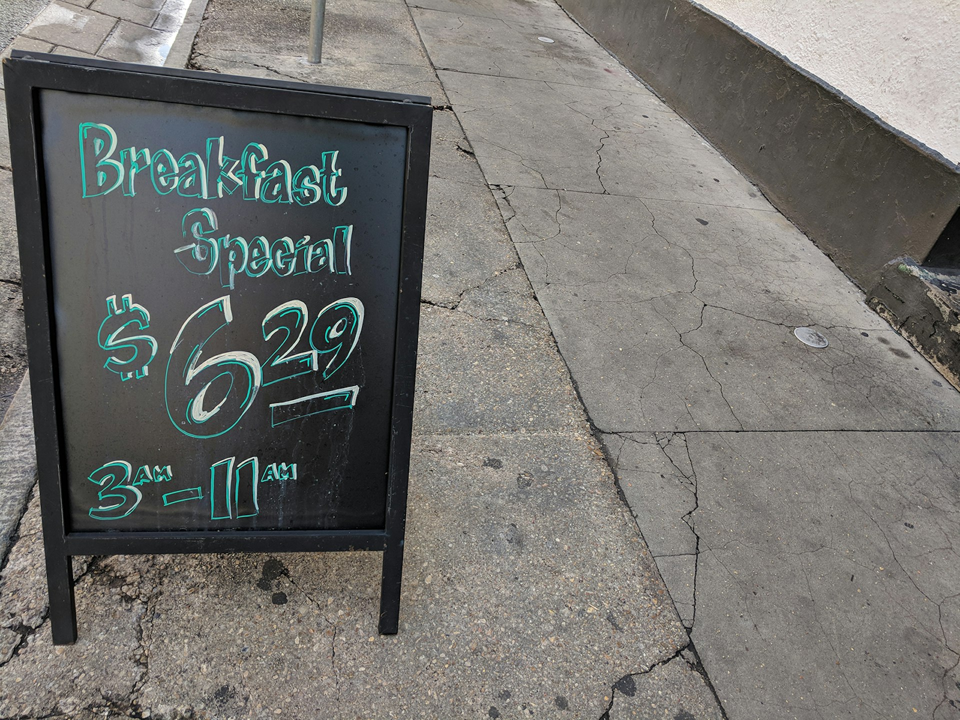 chalk signboard on a cracked sidewalk advertising breakfast from 3am-11am in New Orleans © Adam Karlin / Lonely Planet