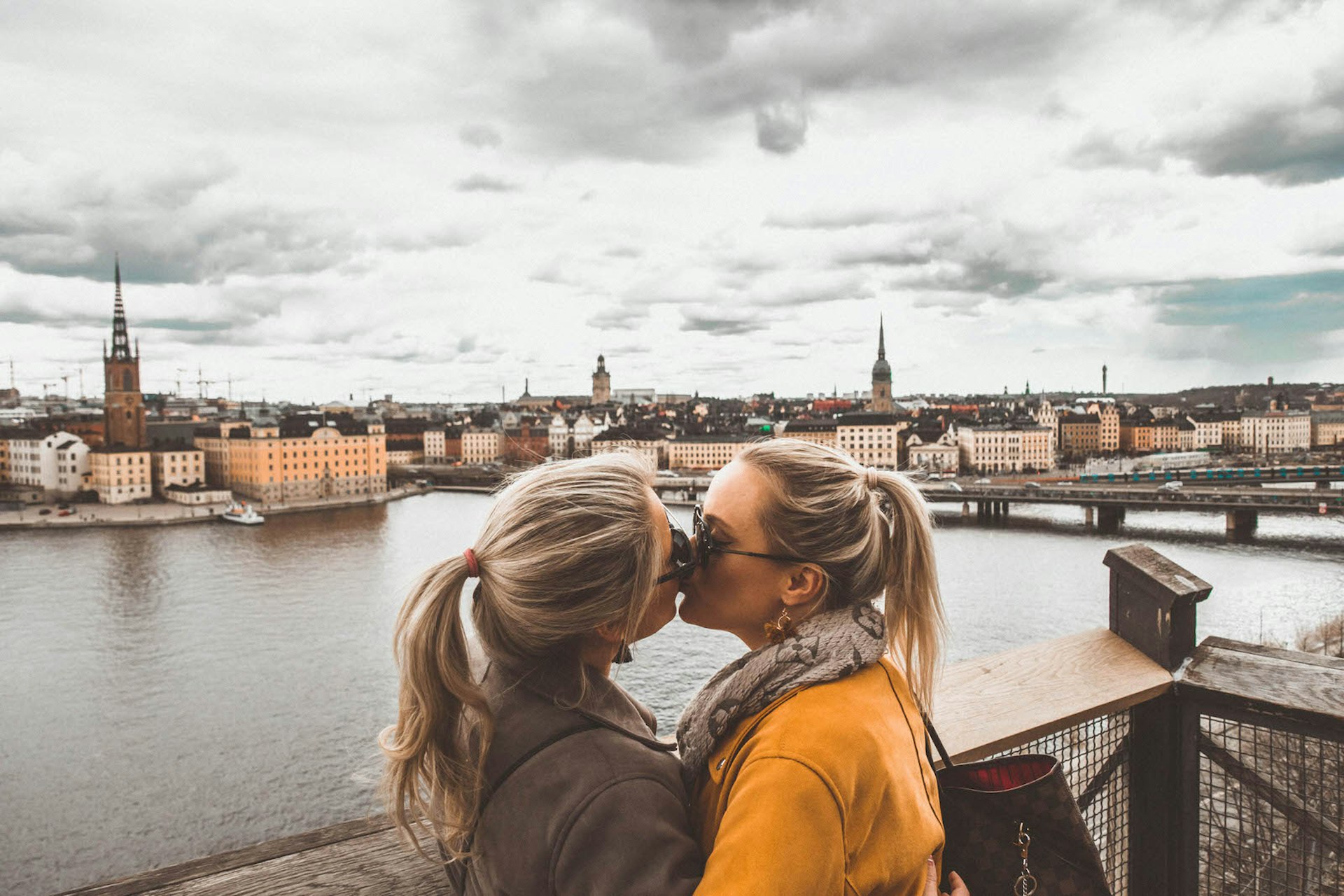 Married couple Whitney & Megan kissing with view of Stockholm behind them © Megan & Whitney Bacon-Evans / Lonely Planet