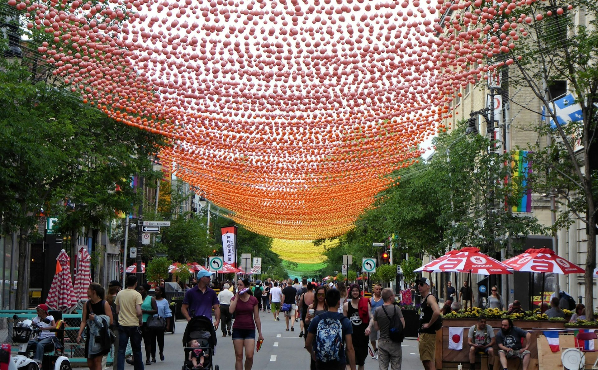 Strings of rainbow colors sway above a pedestrian-only street in Montréal © Jason Najum / Lonely Planet