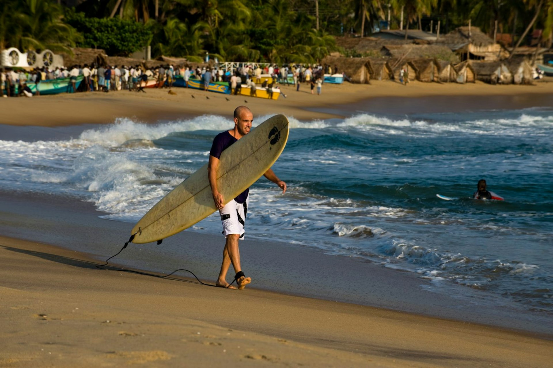 Surfer walking along the beach at Arugam © Kevin Clogstoun / Getty Images