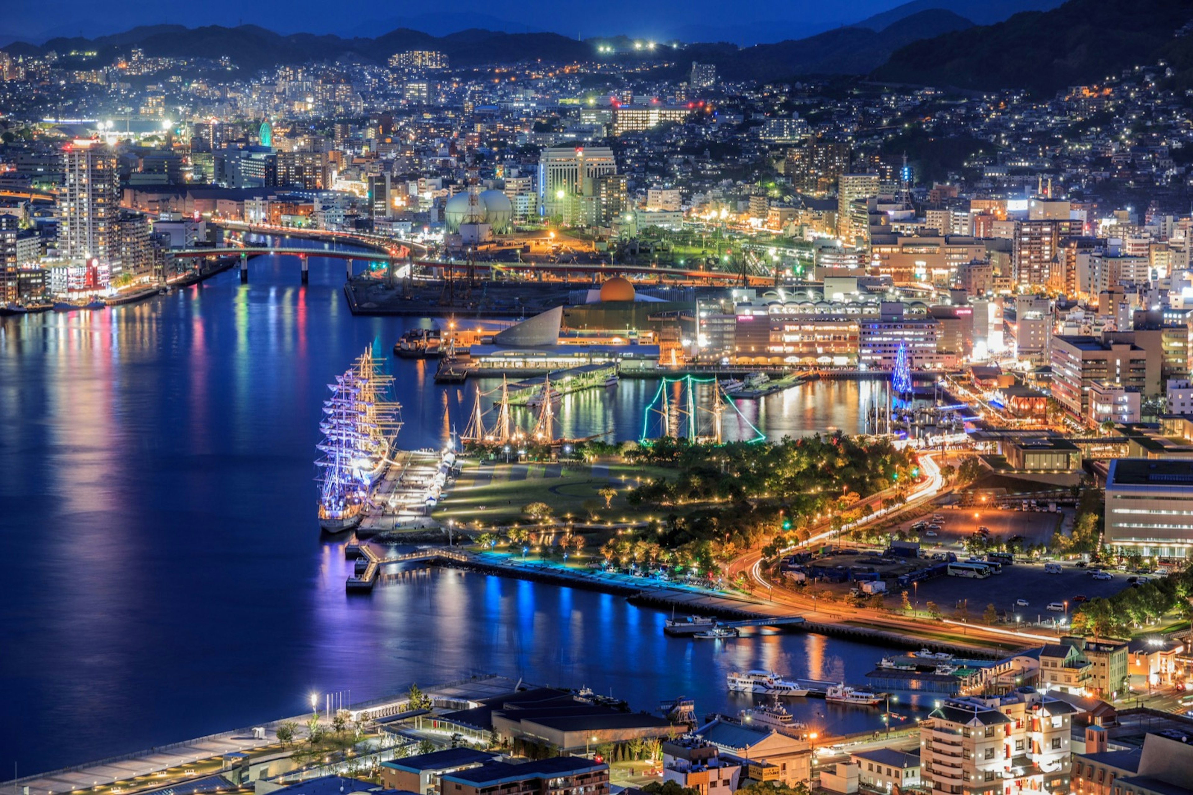 The lights of Nagasaki Harbor illuminate the water with mountains in the background © tomophotography / Getty images