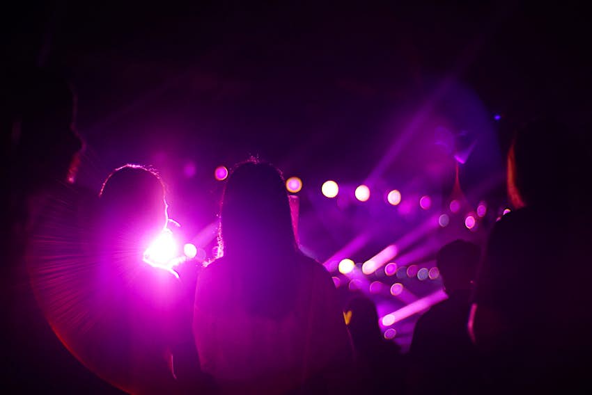 Features - Rear View Of People Enjoying At Music Concert Dark interior of nightclub with crowd and pink lasers