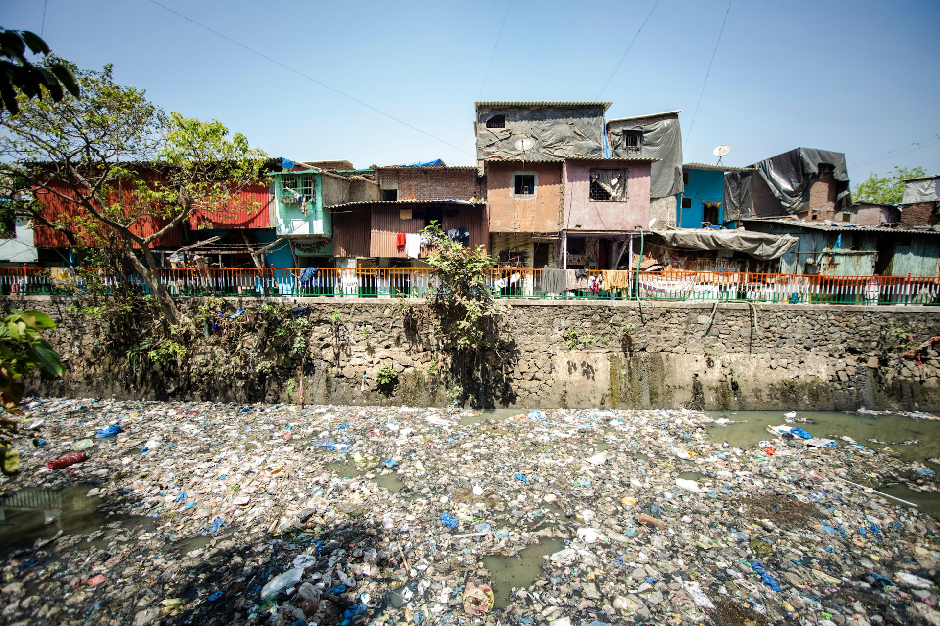 Slums sit on the edge of an urban river polluted with waste in Dharavi slums, Mumbai.