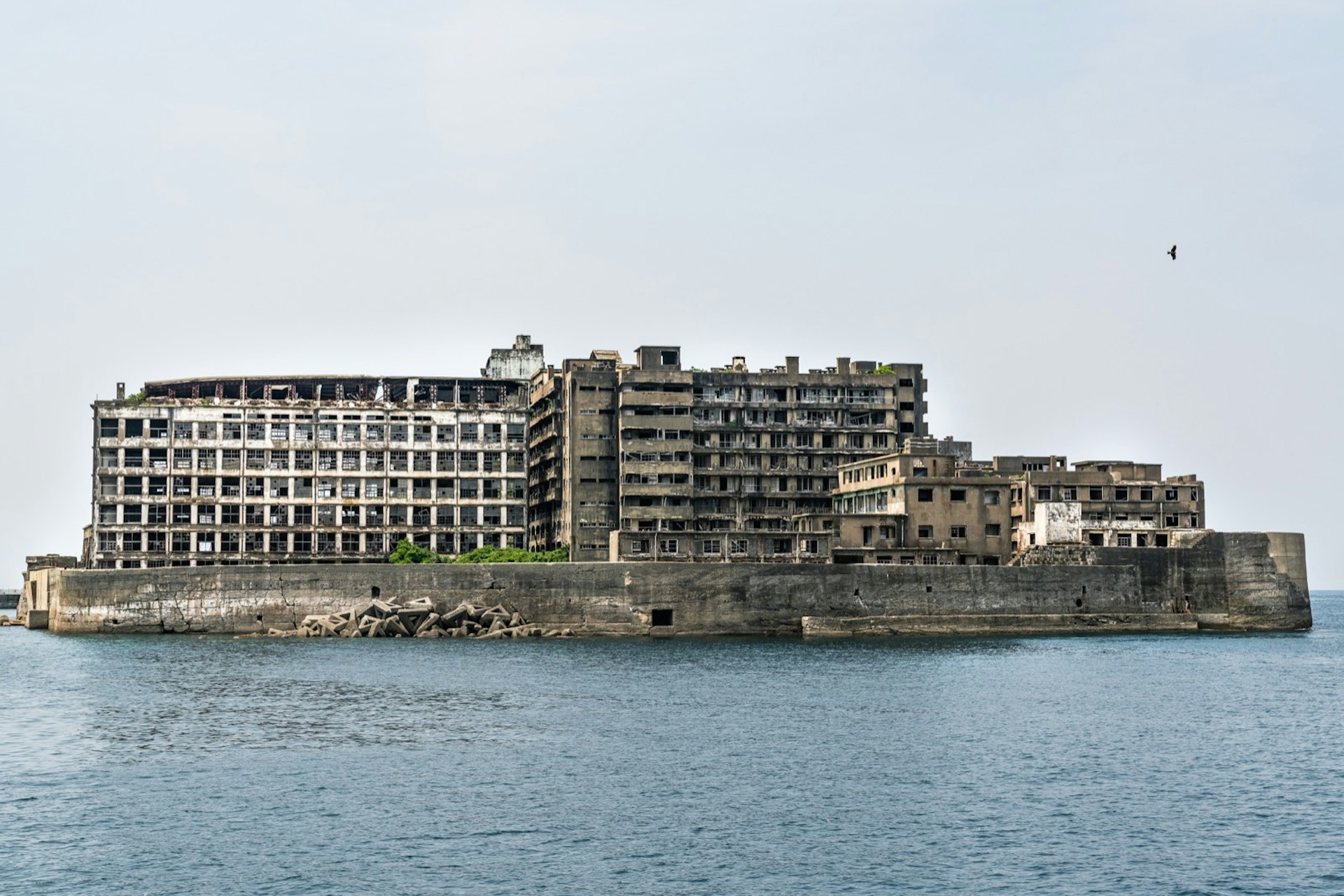 An abandoned island, with decaying buildings is seen in the middle of a calm bay © James Gabriel Martin / Lonely Planet