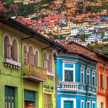 A row of multicolored houses against the backdrop of houses on a hillside in Quito © Mike Matthews Photography / Getty Images