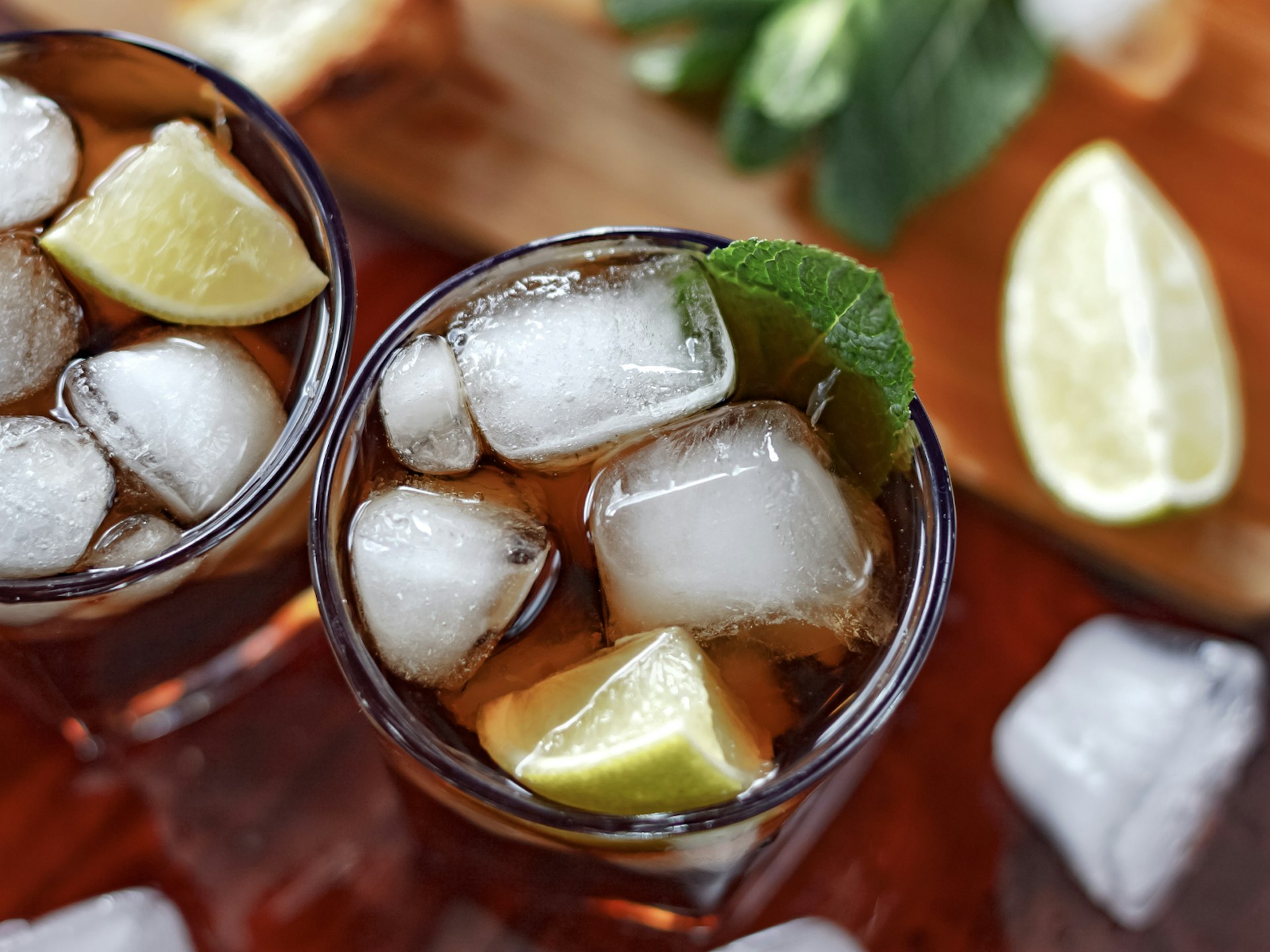 An aerial view of a glass of rum with ice cubes and lime