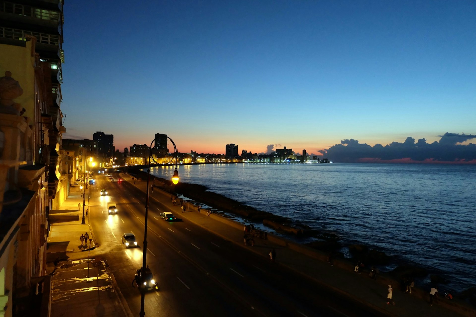 Cars driving along Havana's seafront at dusk