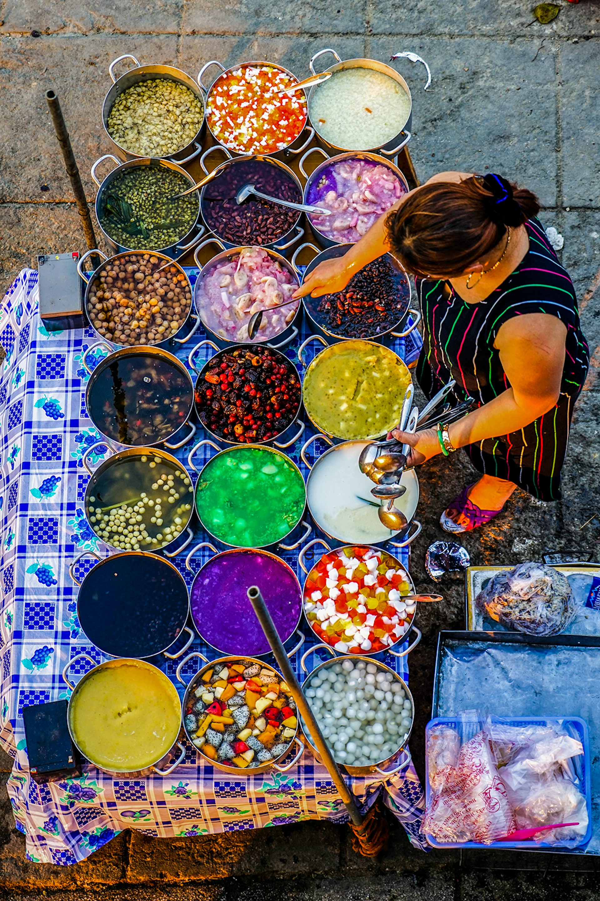 A woman tends to several pots filled with different-colored sweets © James Pham / Lonely Planet