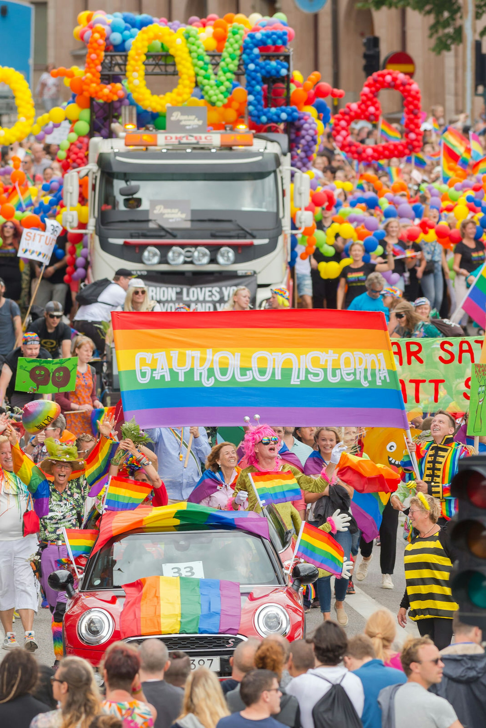 Truck with balloons spelling 'love', surrounded by crowds of marchers, at the Stockholm Pride Parade in 2017 © Stefan Holm / Shutterstock