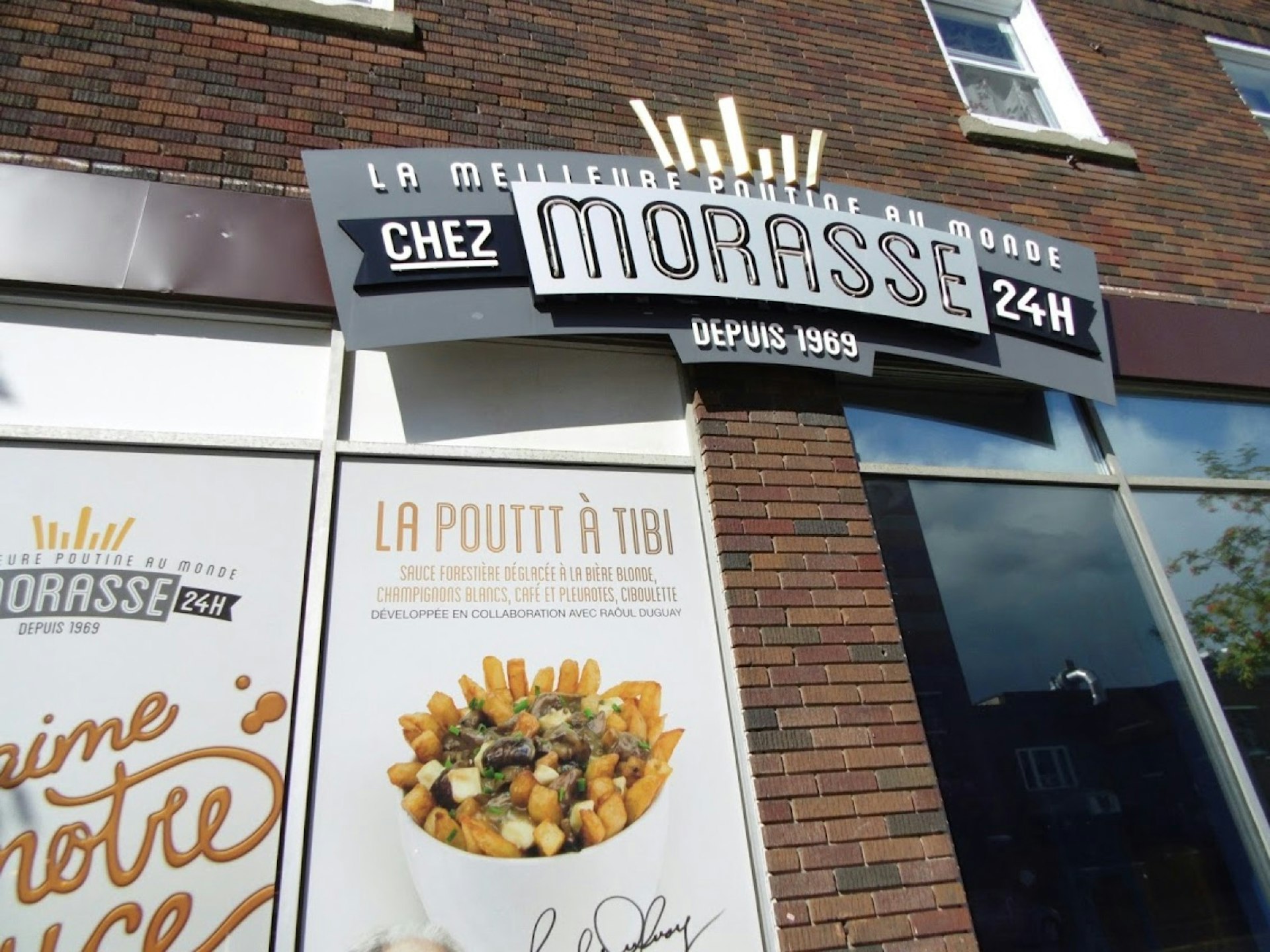 The exterior of the Chez Morasse eatery is shown, with a prominent advertisement for french fries and gravy in the window @ Fiona Tapp / Lonely Planet