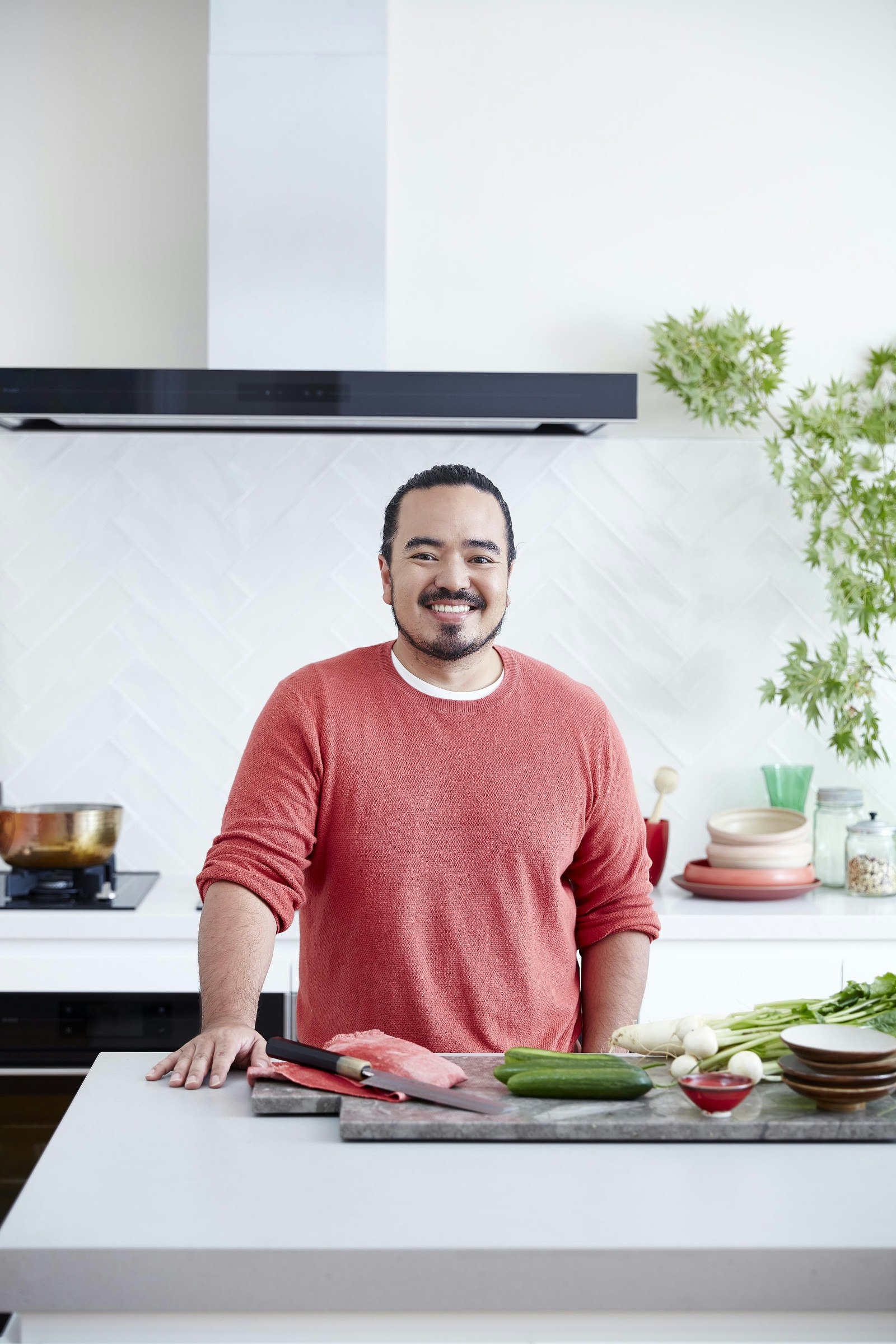 Adam Liaw standing behind a kitchen counter with ingredients on it © Adam Liaw