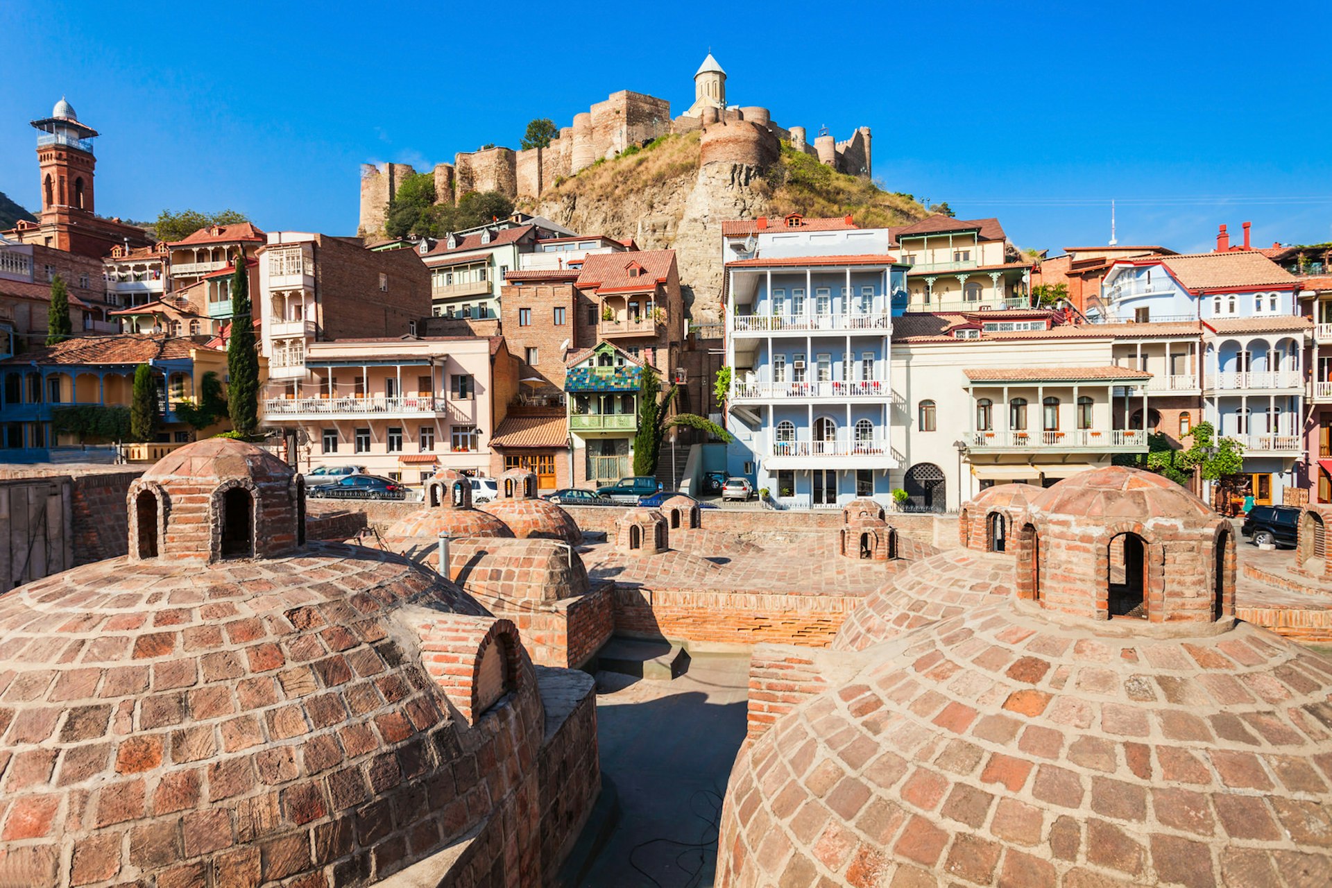 View of Tbilisi's Old Town looking up from the domed roof of the sulphur baths towards colourful houses and the hilltop Narikala Fortress