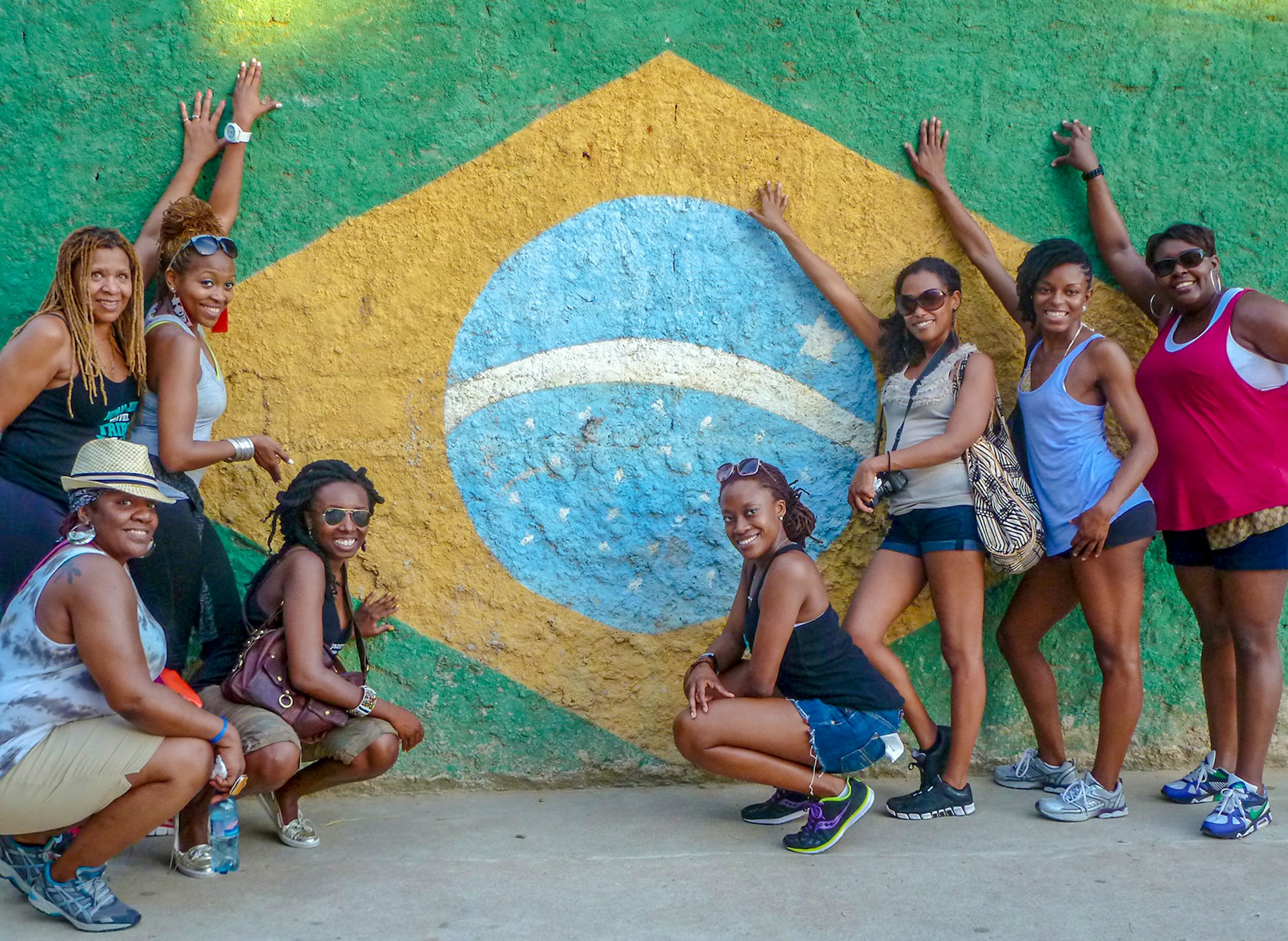 Women stand in front of a mural depicting the Brazilian flag © Nomadness
