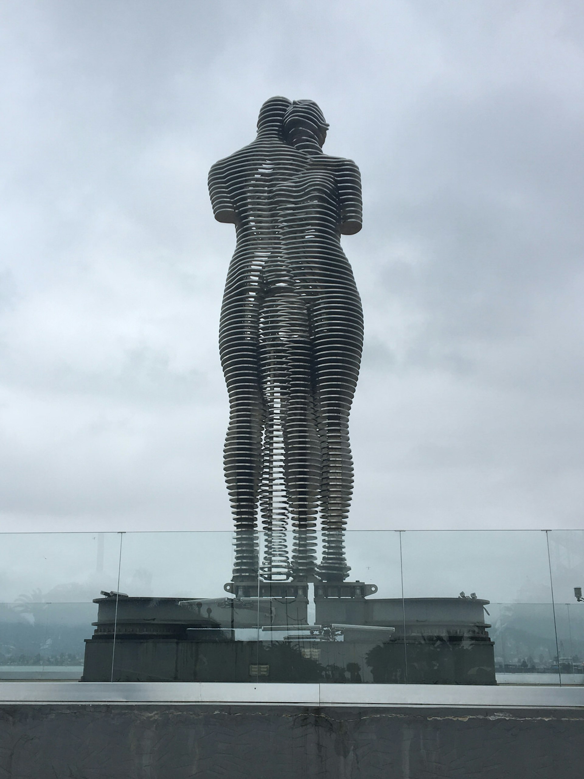 A large metallic sculpture depicting two standing figures merging into each other