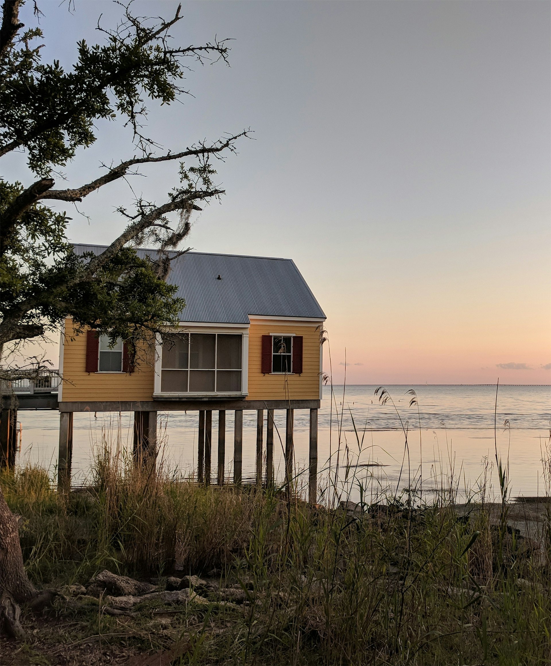 A cabin sits on stilts at sunset on the shore of Lake Pontchartrain in Louisiana © Adam Karlin / Lonely Planet