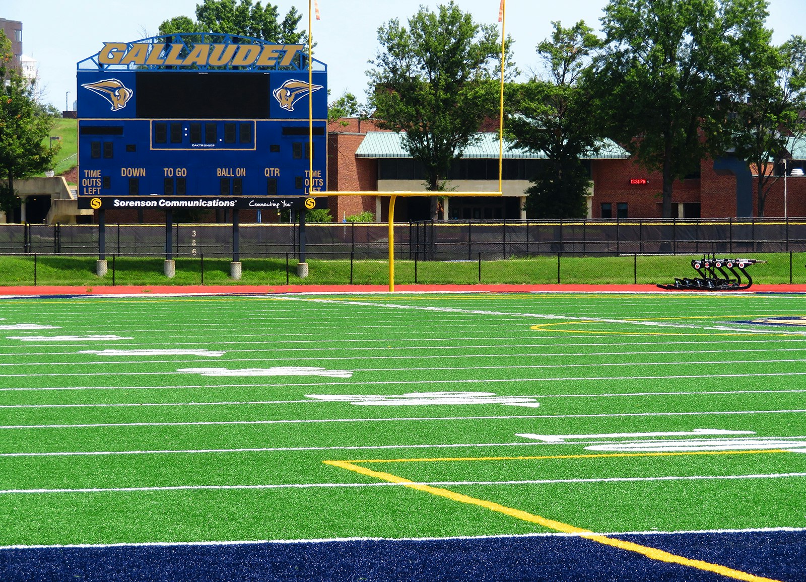 Bright green grass and crisp white numbers mark the yard lines on a football field, with the Gallaudet scoreboard in the background © Barbara Noe Kennedy / Lonely Planet
