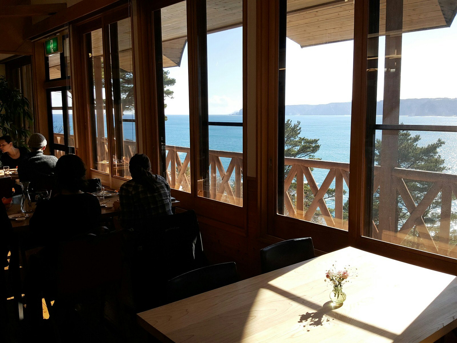 View from inside a restaurant looking through large windows to the blue ocean and cliffs beyond