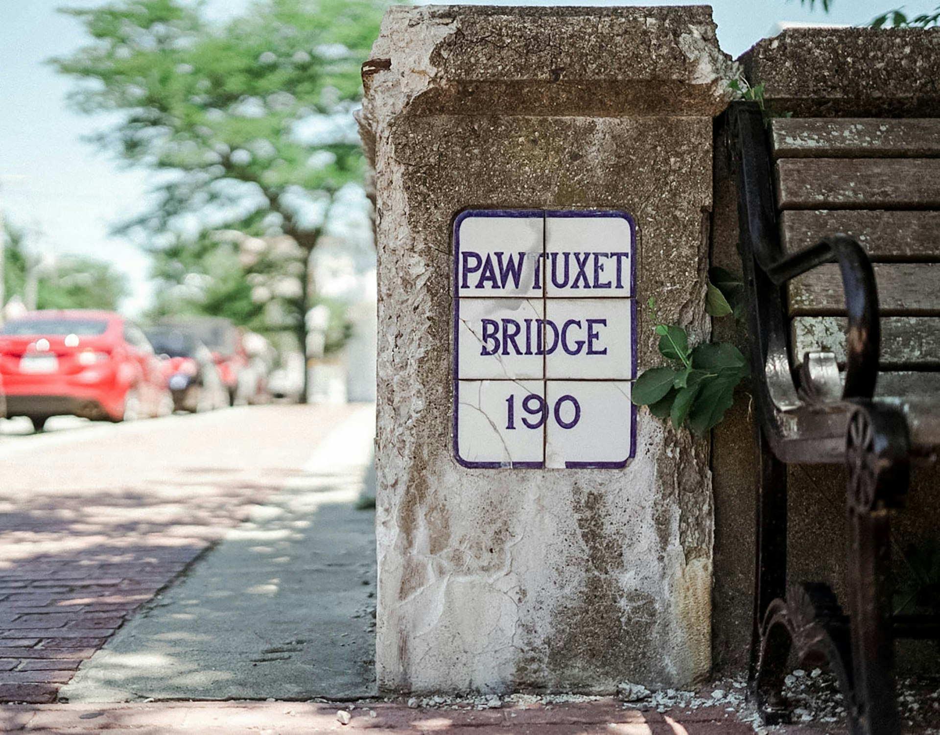 Close-up shot of a vintage Pawtuxet Bridge sign next to a bench in Rhode Island © Anna Saxon / Lonely Planet