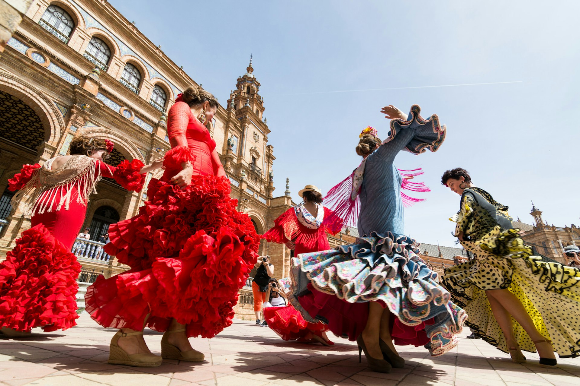 Young women dressed in traditional outfits dance flamenco on Plaza de Espana, Seville, Spain © leonov.o / Shutterstock