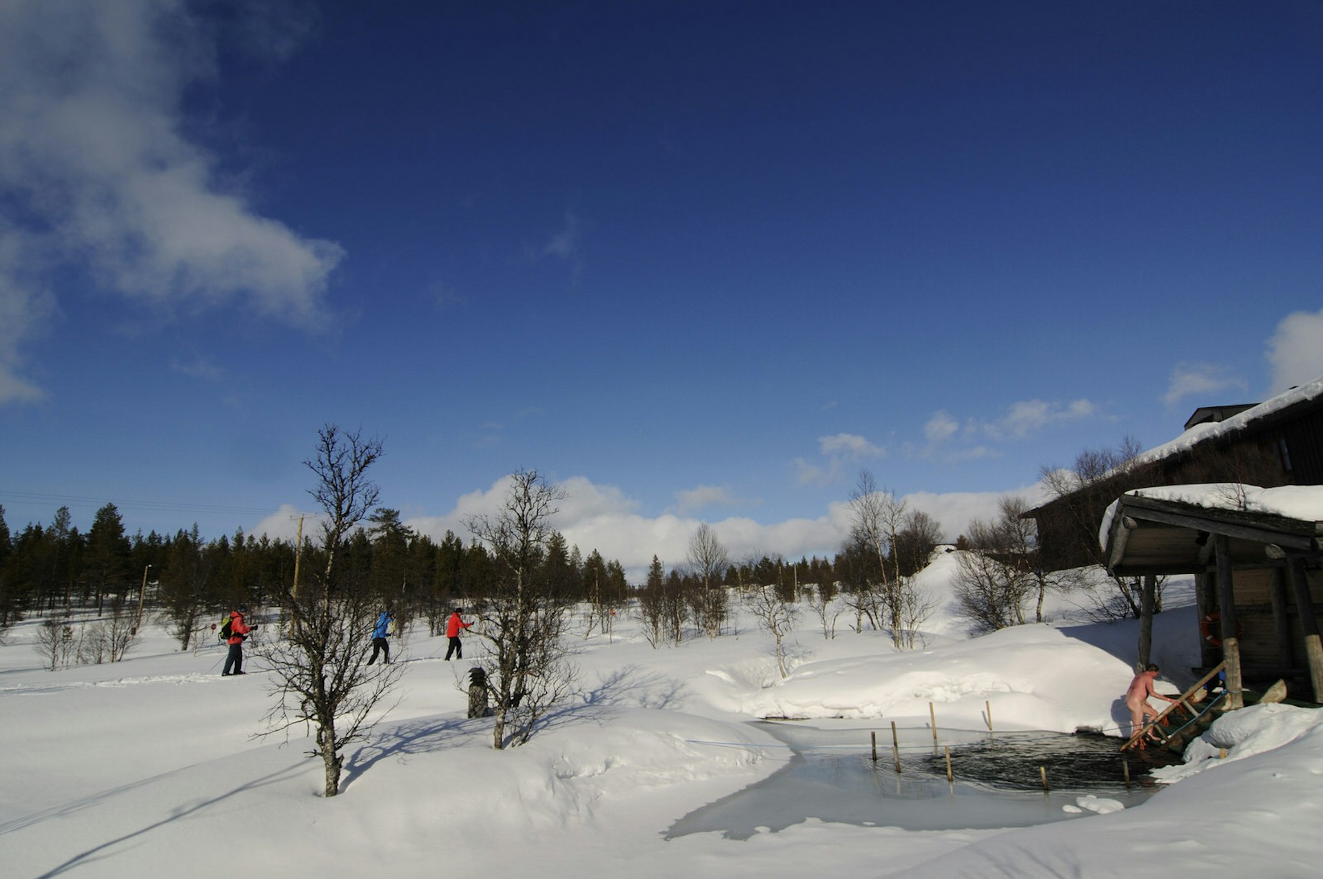 A sauna-goer emerges after a plunge in icy water beside a steam sauna in Urho Kekkonen National Park, close to Saariselkä.