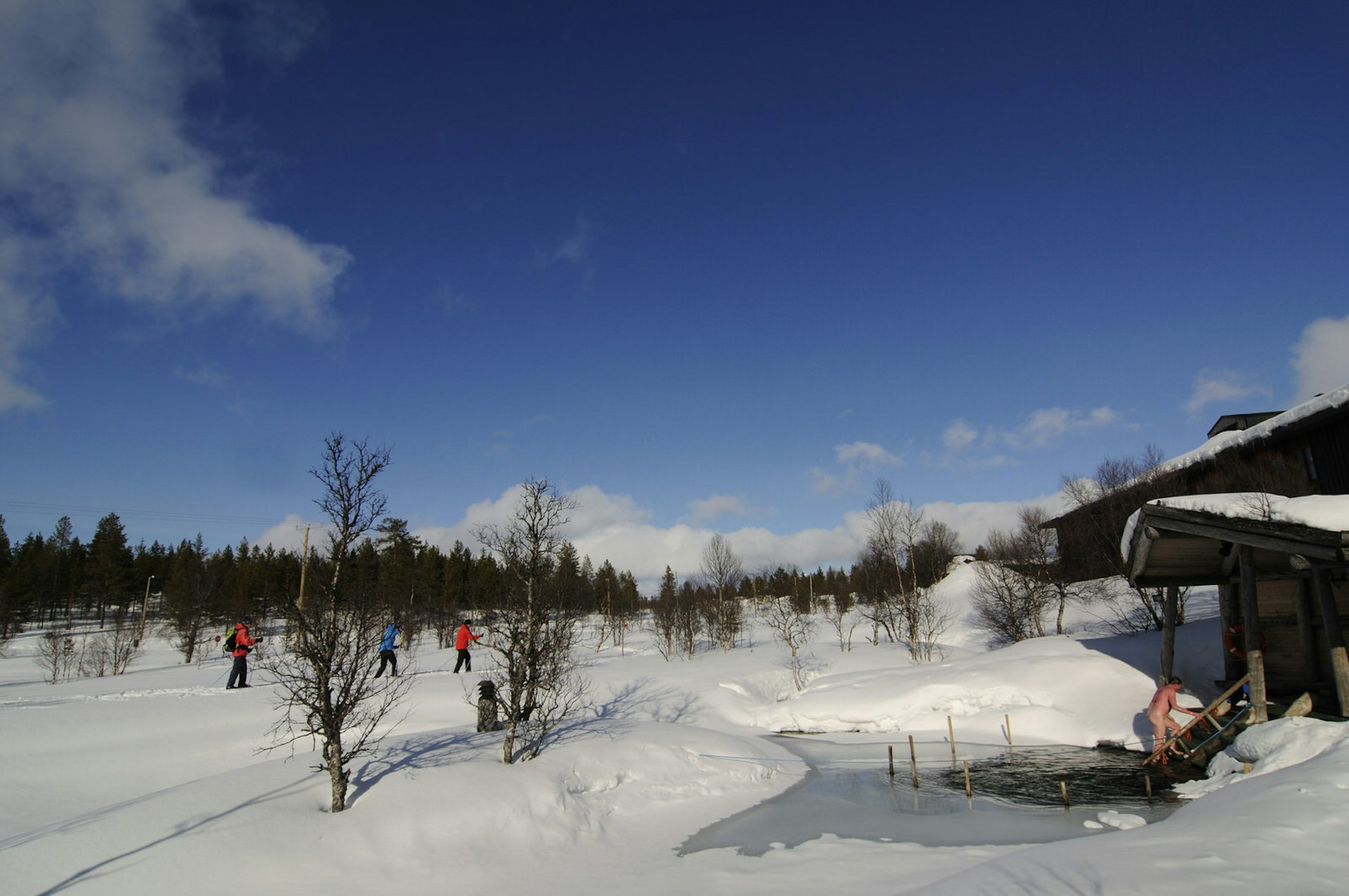 A sauna-goer emerges after a plunge in icy water beside a steam sauna in Urho Kekkonen National Park, close to Saariselkä. 