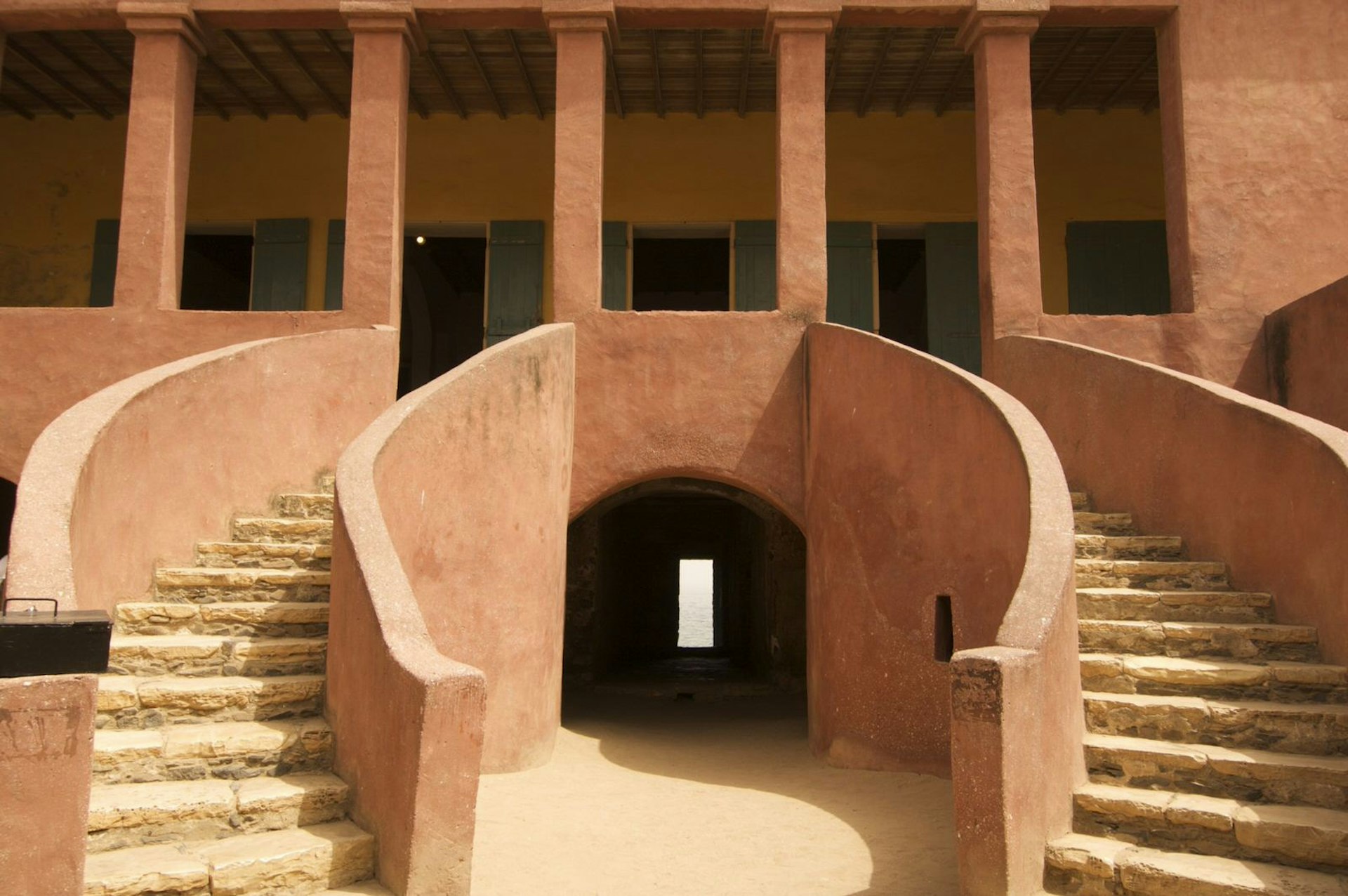 Taken from La Maison des Esclaves courtyard on Gorée, this image looks up the twin, curving staircases and through a dark passage between the stairs. A small opening appears in the darkness (the doorway to nowhere) © bdinphoenix / Budget Travel