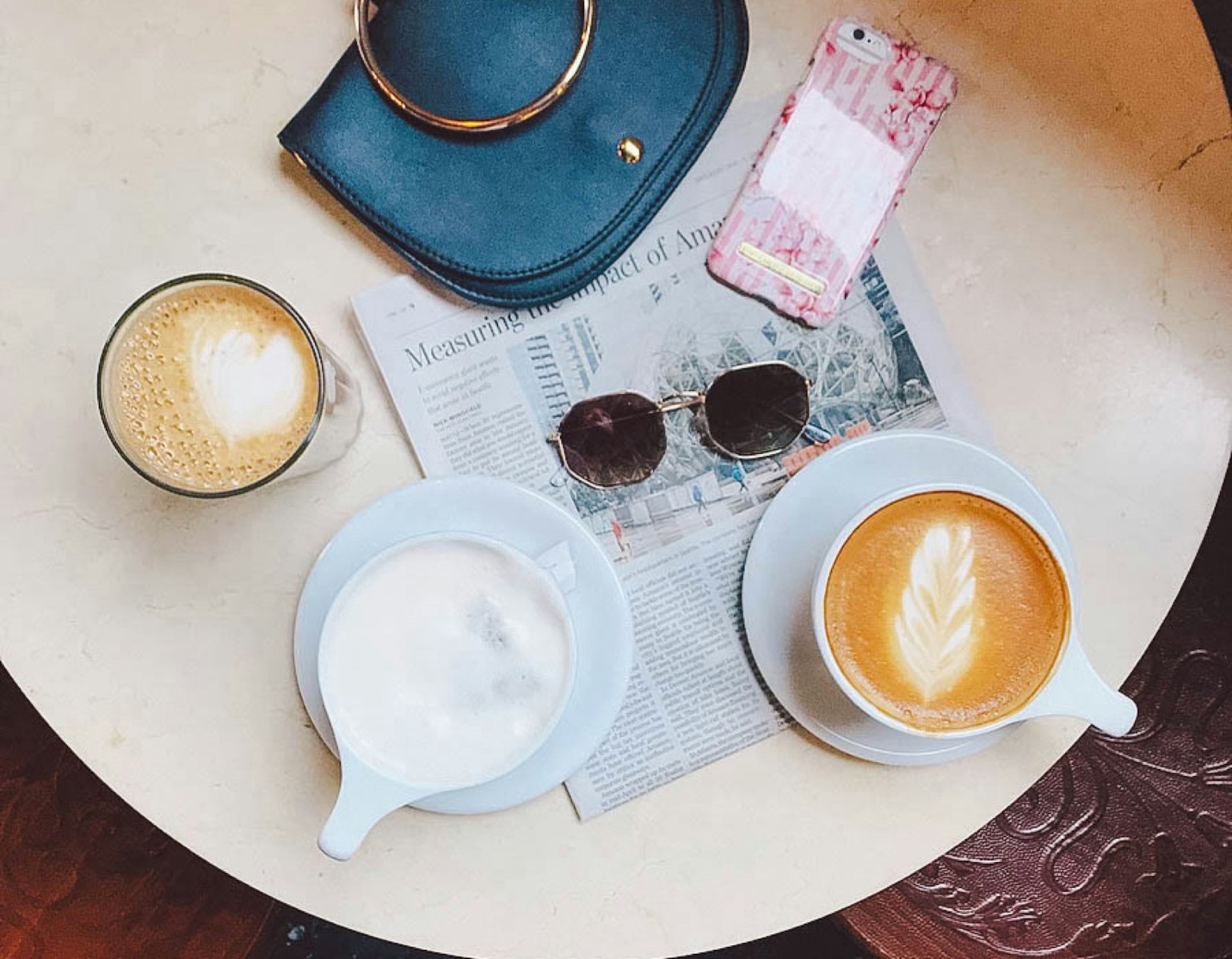 Mugs of coffee sit on a table along with a purse, sunglasses and a newspaper © Jessica Lam / Lonely Planet
