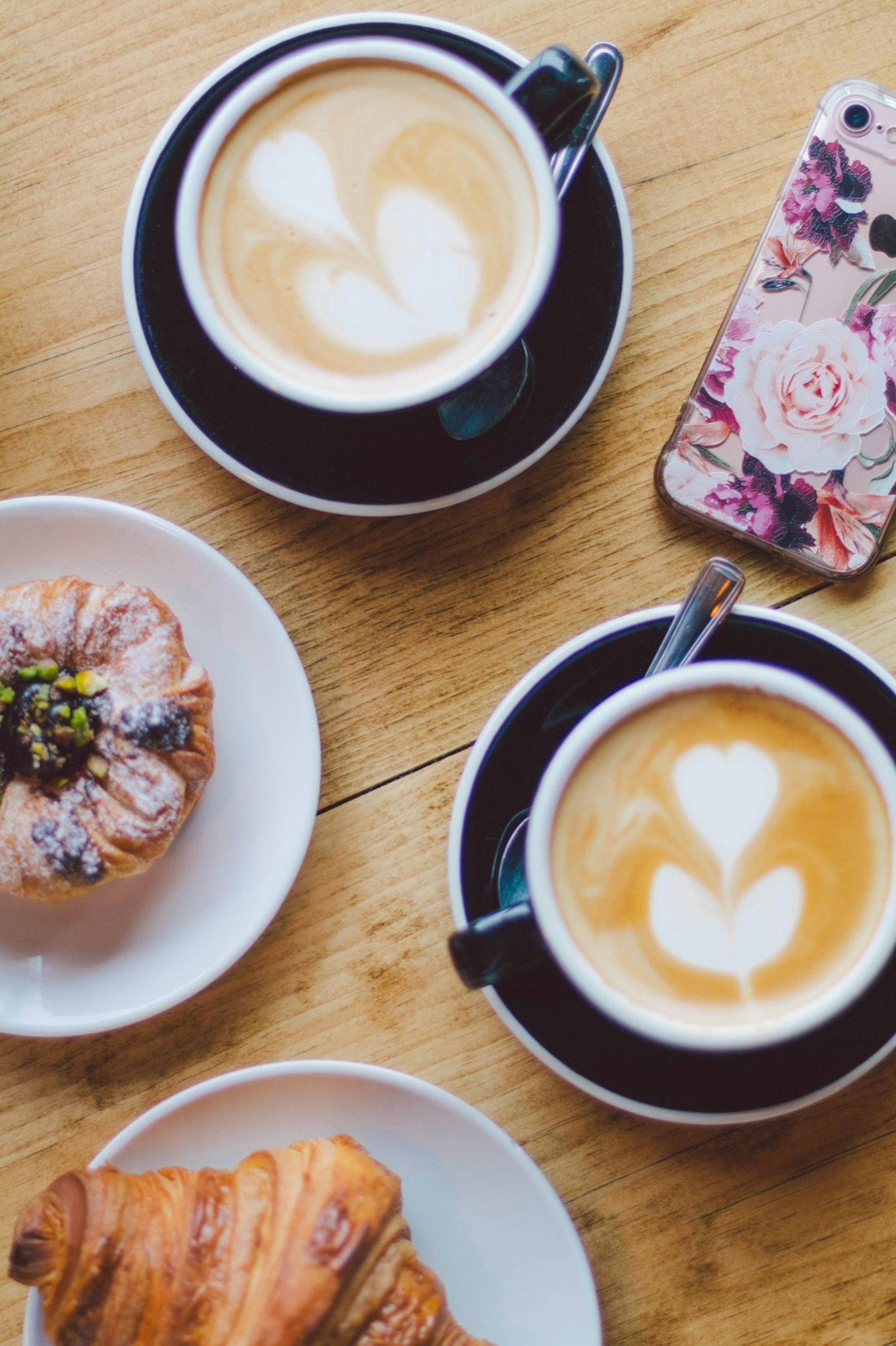 Looking down at two mugs of coffee, with several pastries on plates around © Jessica Lam / Lonely Planet