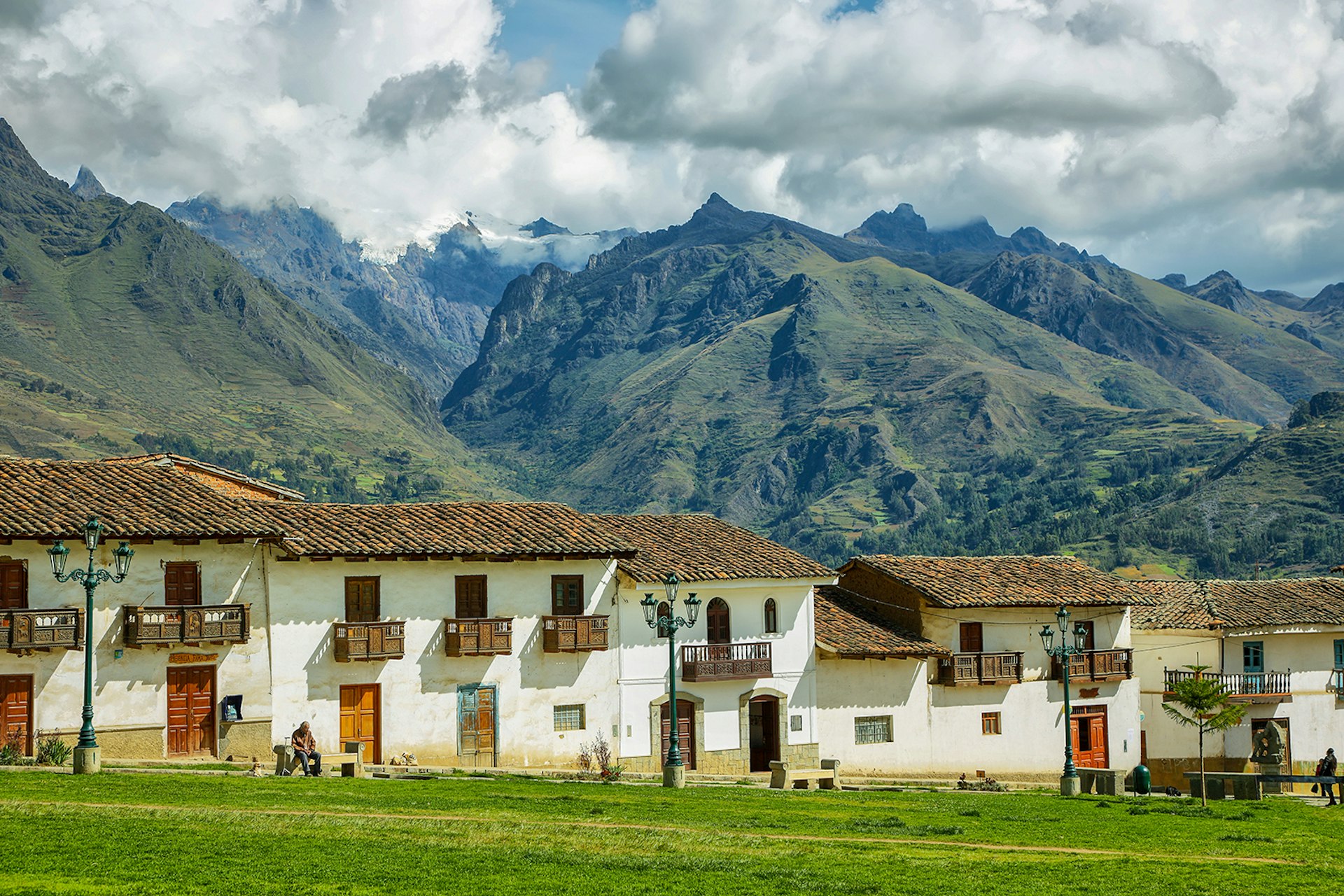 A line of white buildings with brown roofs in Chacas with high green mountains in the background © Estivilml / Getty Images