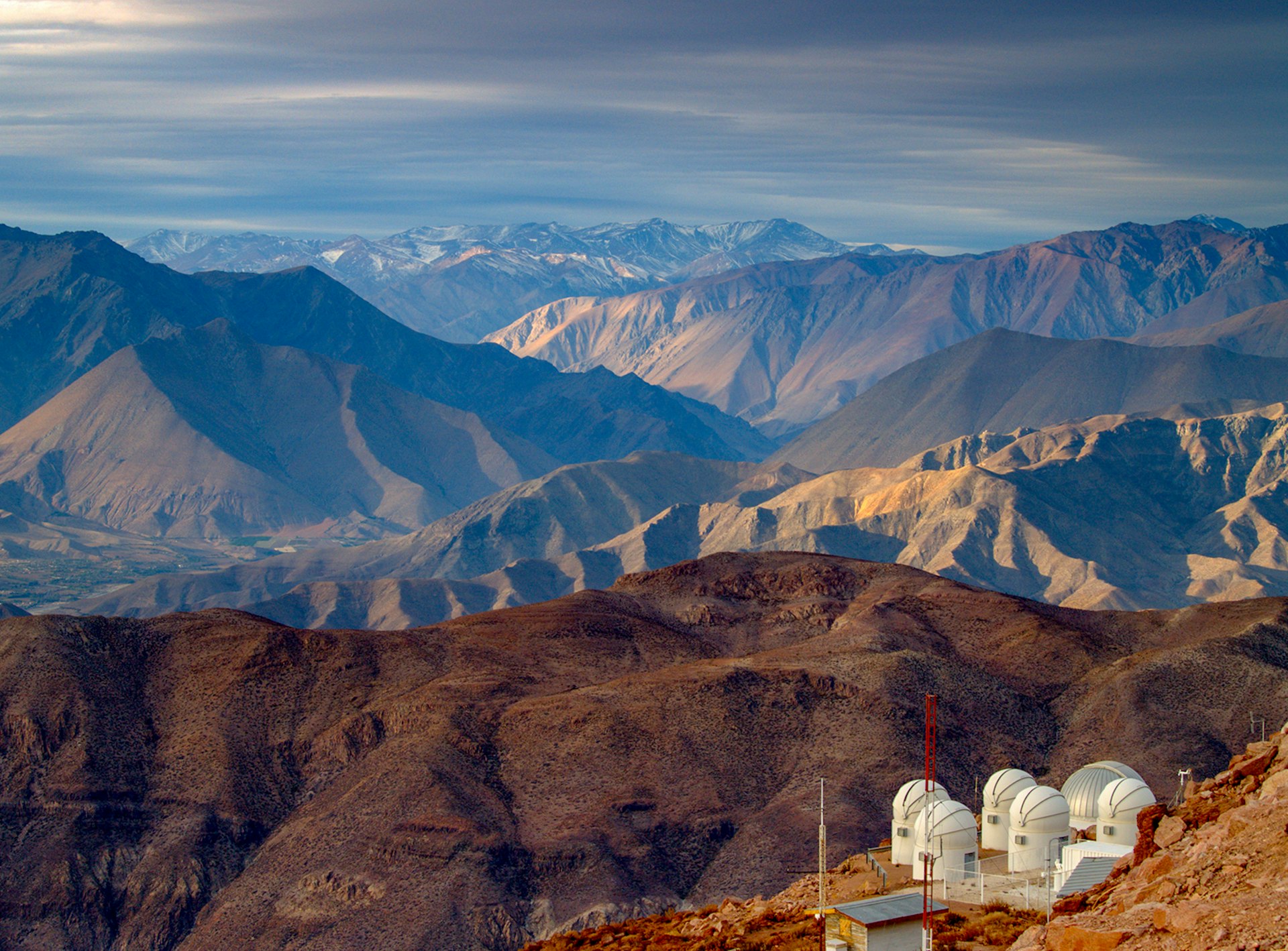 A view of a brown, rocky mountain range with an observatory in the foreground © TimAbbott / Getty Images