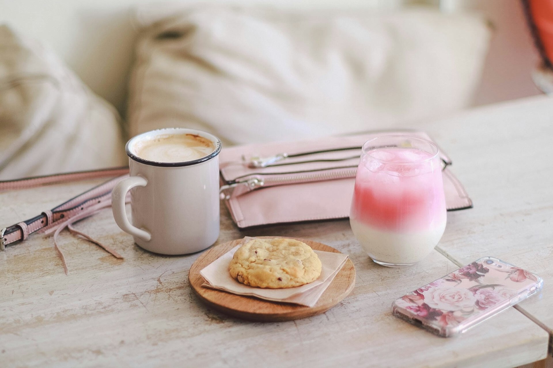 A pale pink drink and a cookie on a plate are seen on a white table © Jessica Lam / Lonely Planet