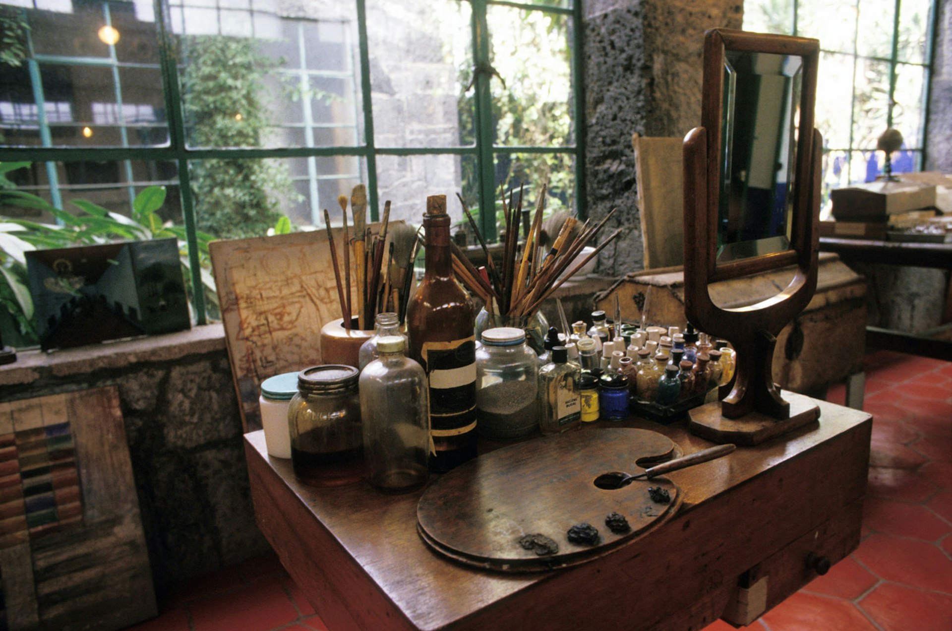 Various paints, brushes and other supplies adorn a desk