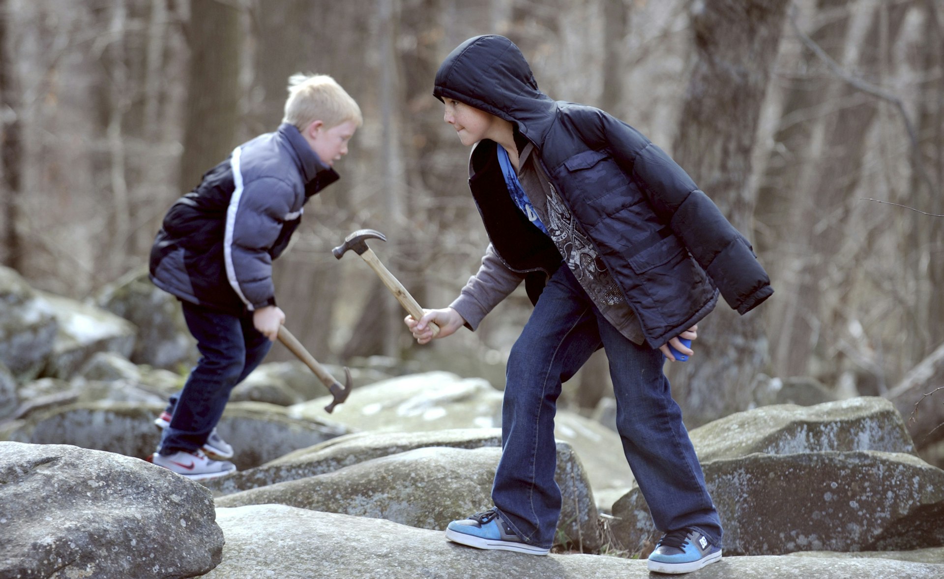 Two boys in winter coats hold hammers and stand on boulders © Allentown Morning Call / Getty Images