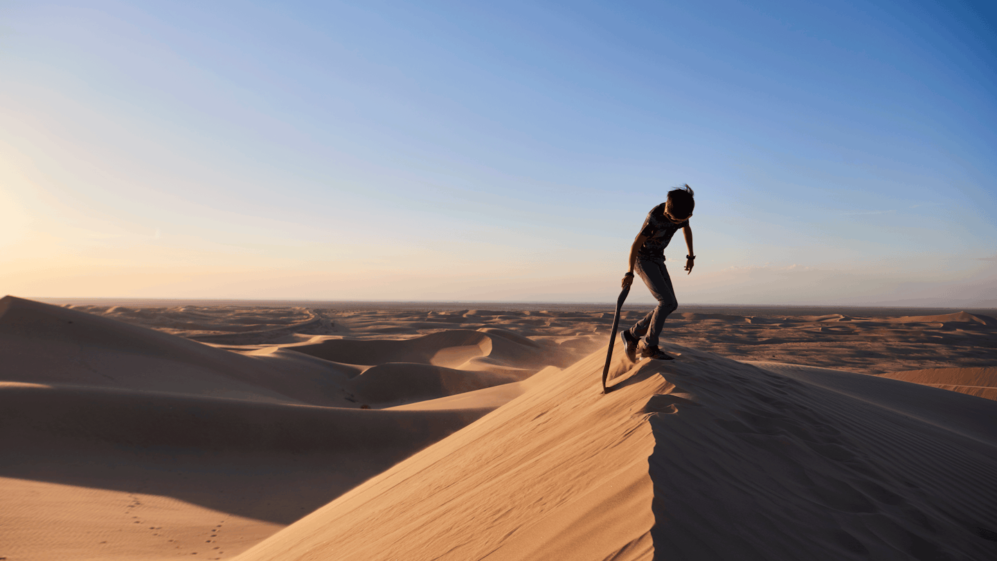 Boy sand surfing in the desert sand dunes in Glarnis California