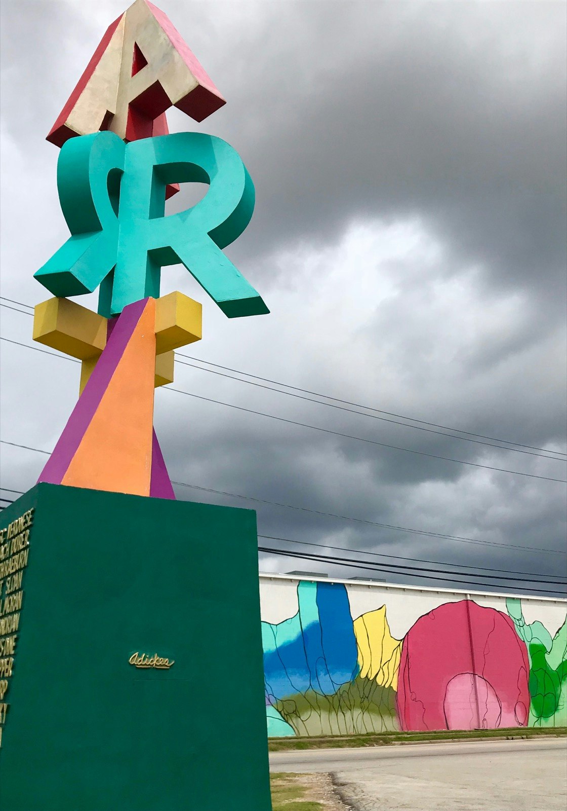 A column of stylized letters spelling 'Art' stands in front of a cloudy gray sky and colorful mural © Lisa Dunford / Lonely Planet