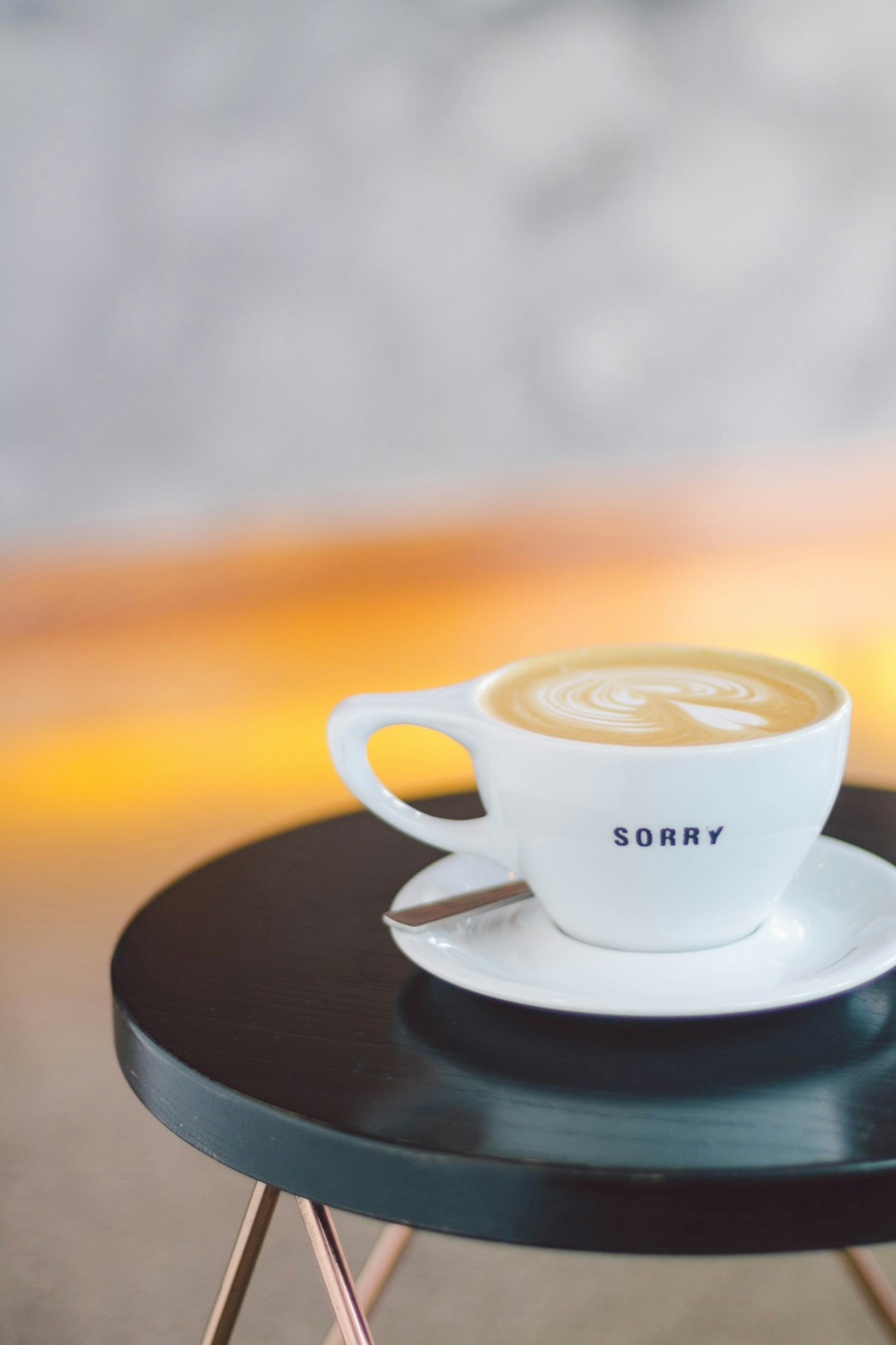 The word 'Sorry' is written on the side of a shallow white mug on a black table © Jessica Lam / Lonely Planet