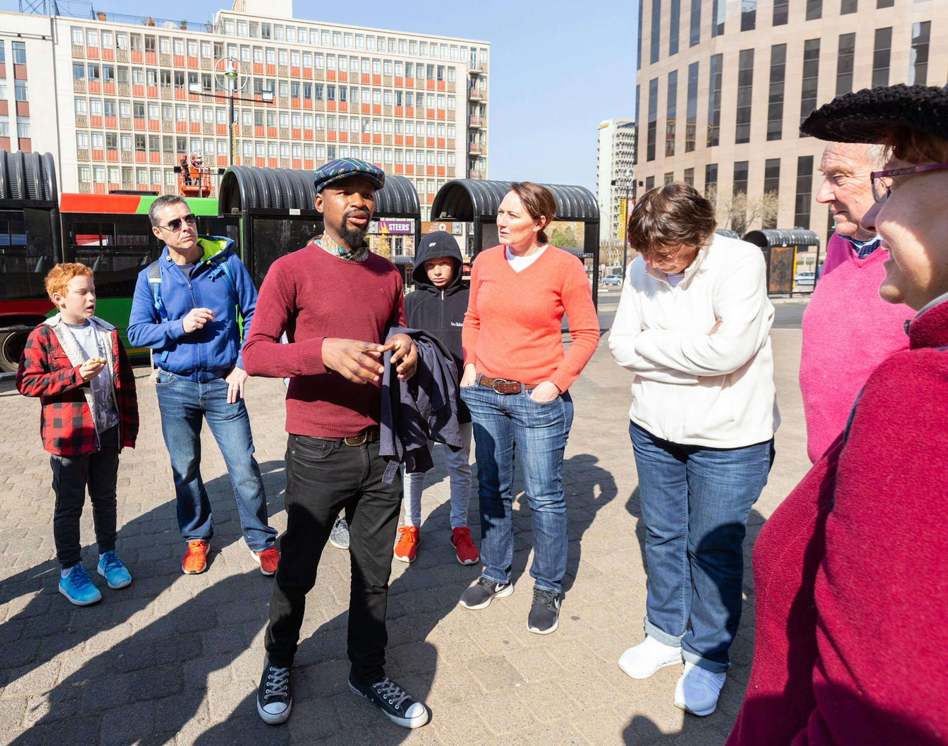 A black South African guide stands in downtown with a group of visitors on one of JoburgPlaces' Johannesburg walking tours © Heather Mason / Lonely Planet