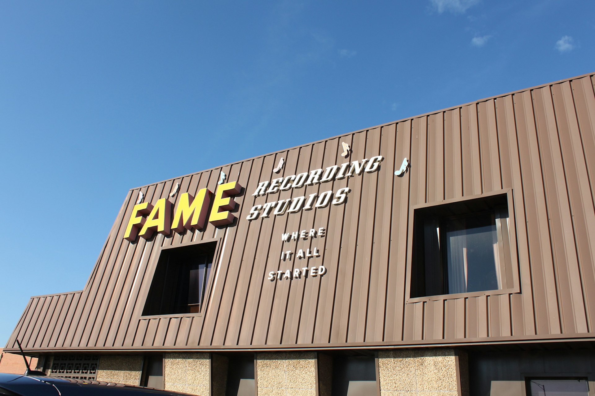 The brown mid-century roofline of Fame Studios is silhouetted against a blue sky. 