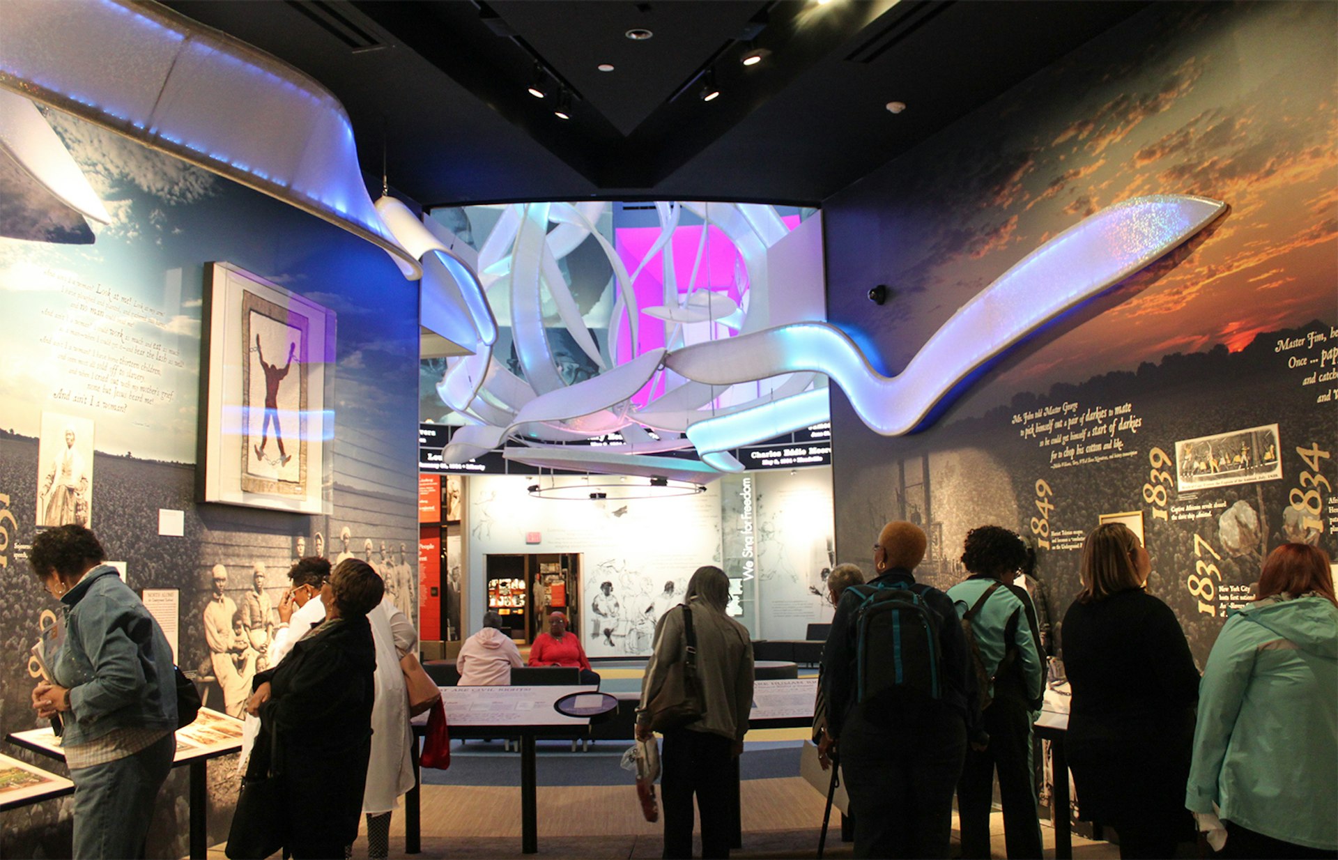 Modern museum interior with a handful of people clustered around various exhibits