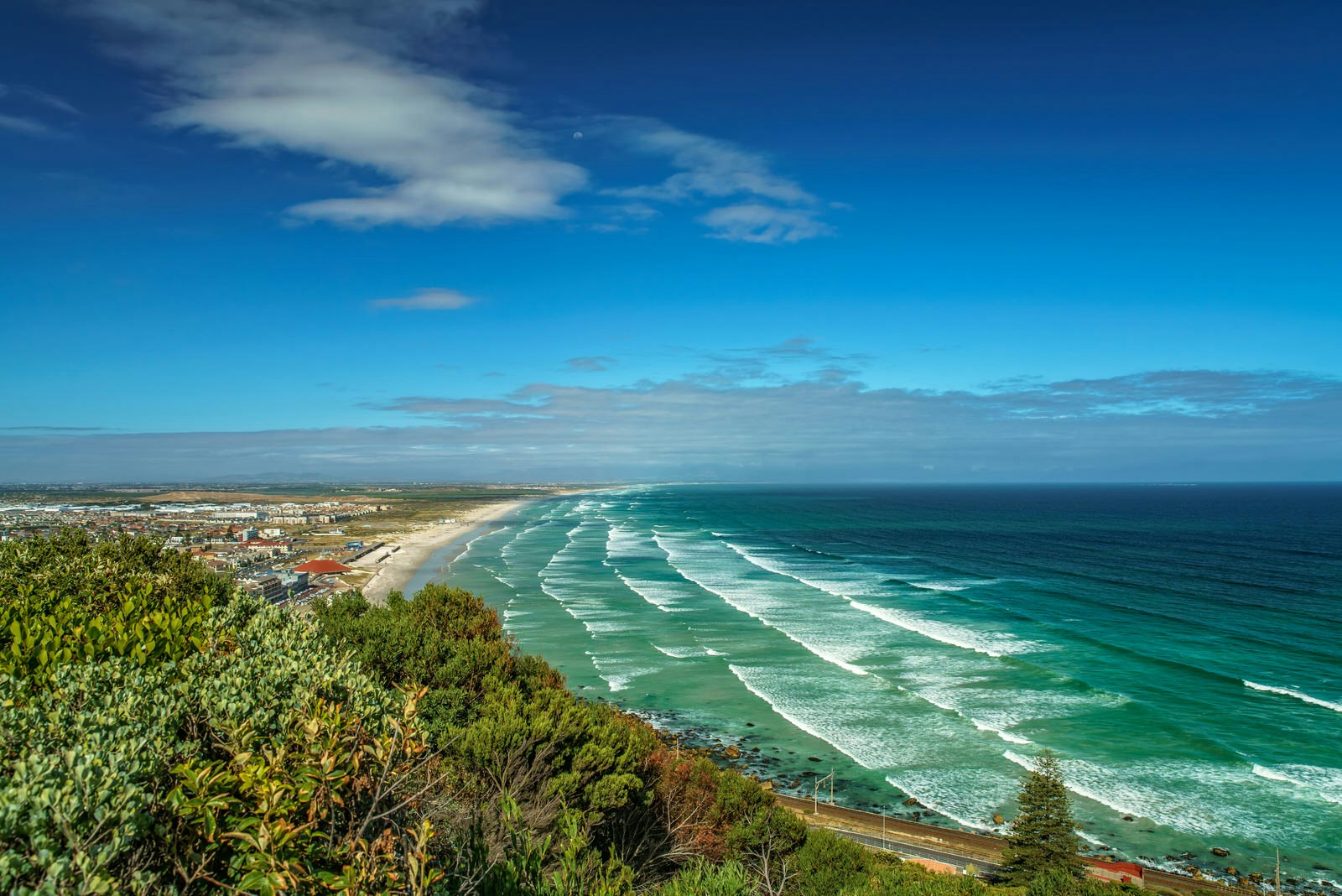 Looking down over the coast, with ocean on the right and the Cape on the left - line after line of waves roll into Muizenberg Beaach © Achim Thomae / Getty Images
