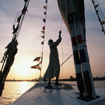 Features - Egypt, Aswan, man sailing felucca on River Nile, sunset
