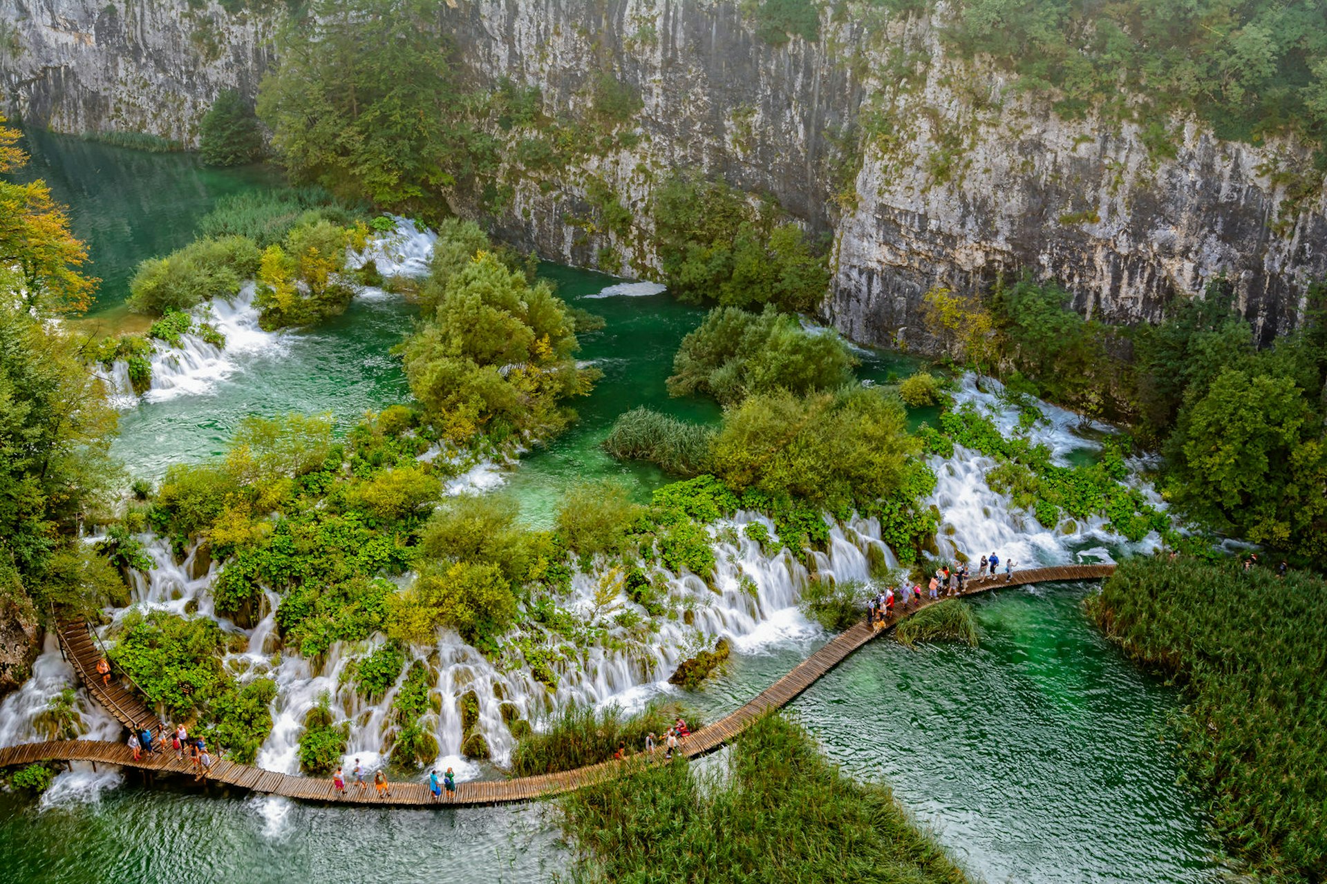 A shot from above showing tourist walking along a winding boardwalk past cascades of water © Richard Guijt Photography / Shutterstock