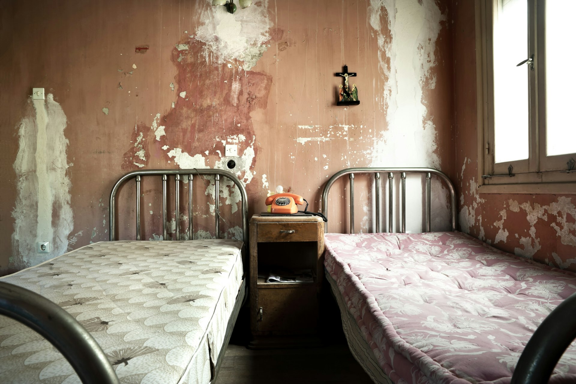 A dirty hotel room with unmade beds and bare walls © Antlio / Shutterstock
