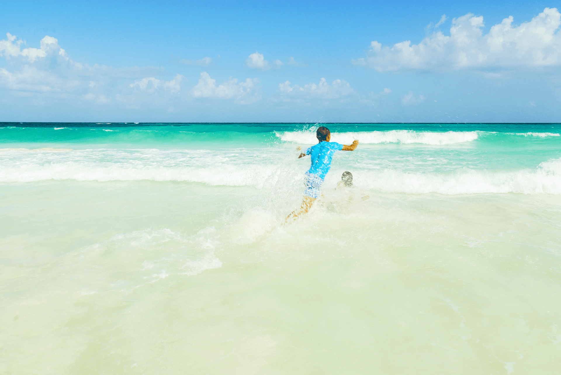 Two children play in the waves on an empty beach © ahuau19969 / Shutterstock