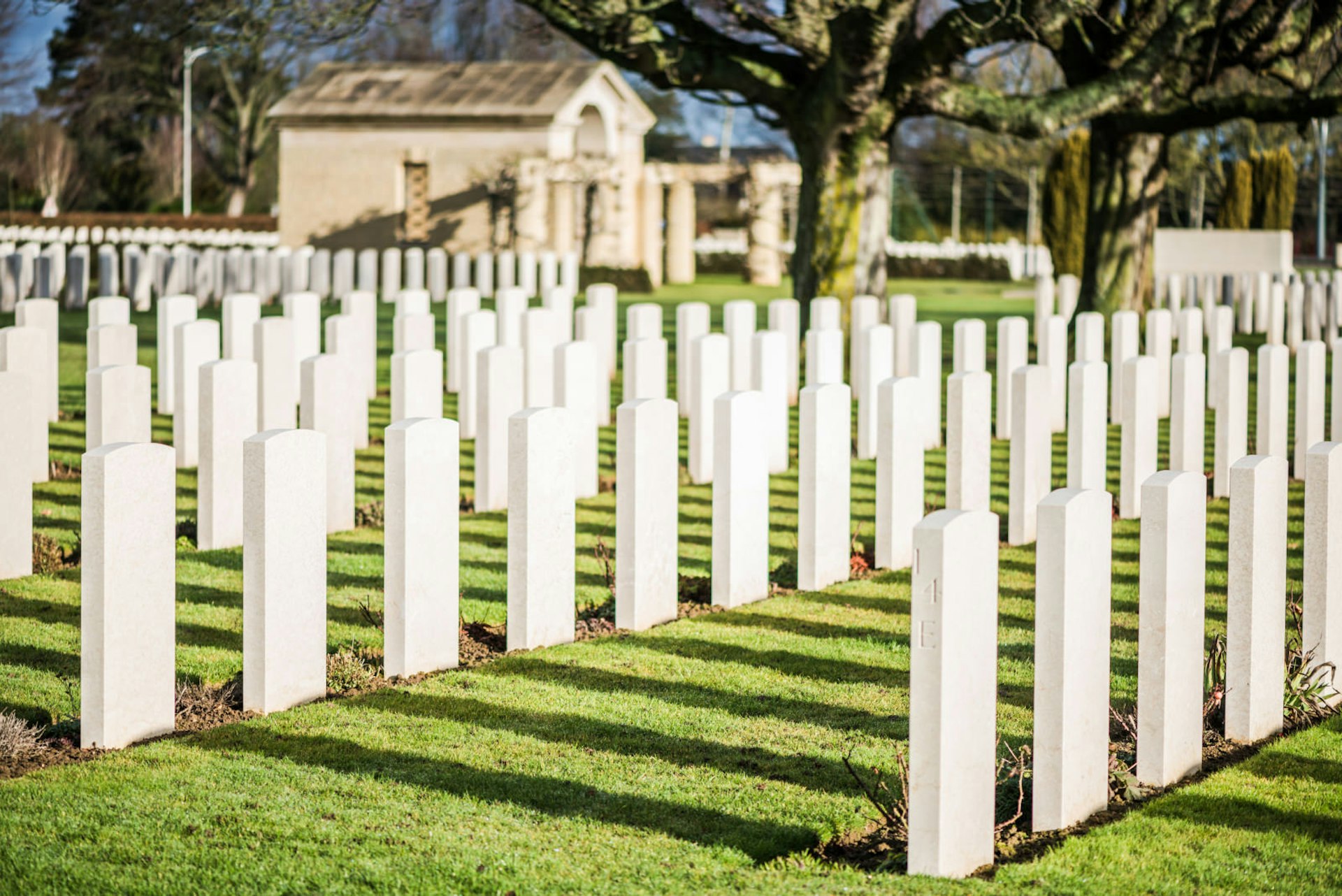 Rows of gravestones stand starkly on a sunny day at the Bayeux War Cemetery