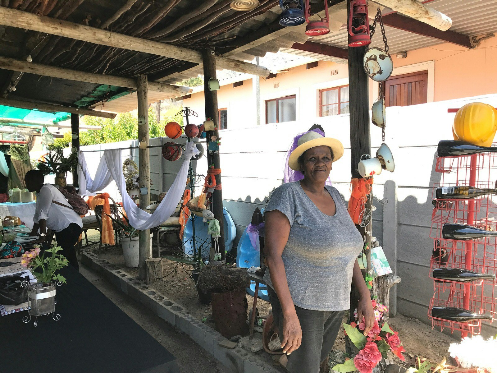 South African Sienna 'Aunty' Charles stands in the foreground of her open-walled restaurant, which is dotted with quirky knick-knacks © Simon Richmond / Lonely Planet