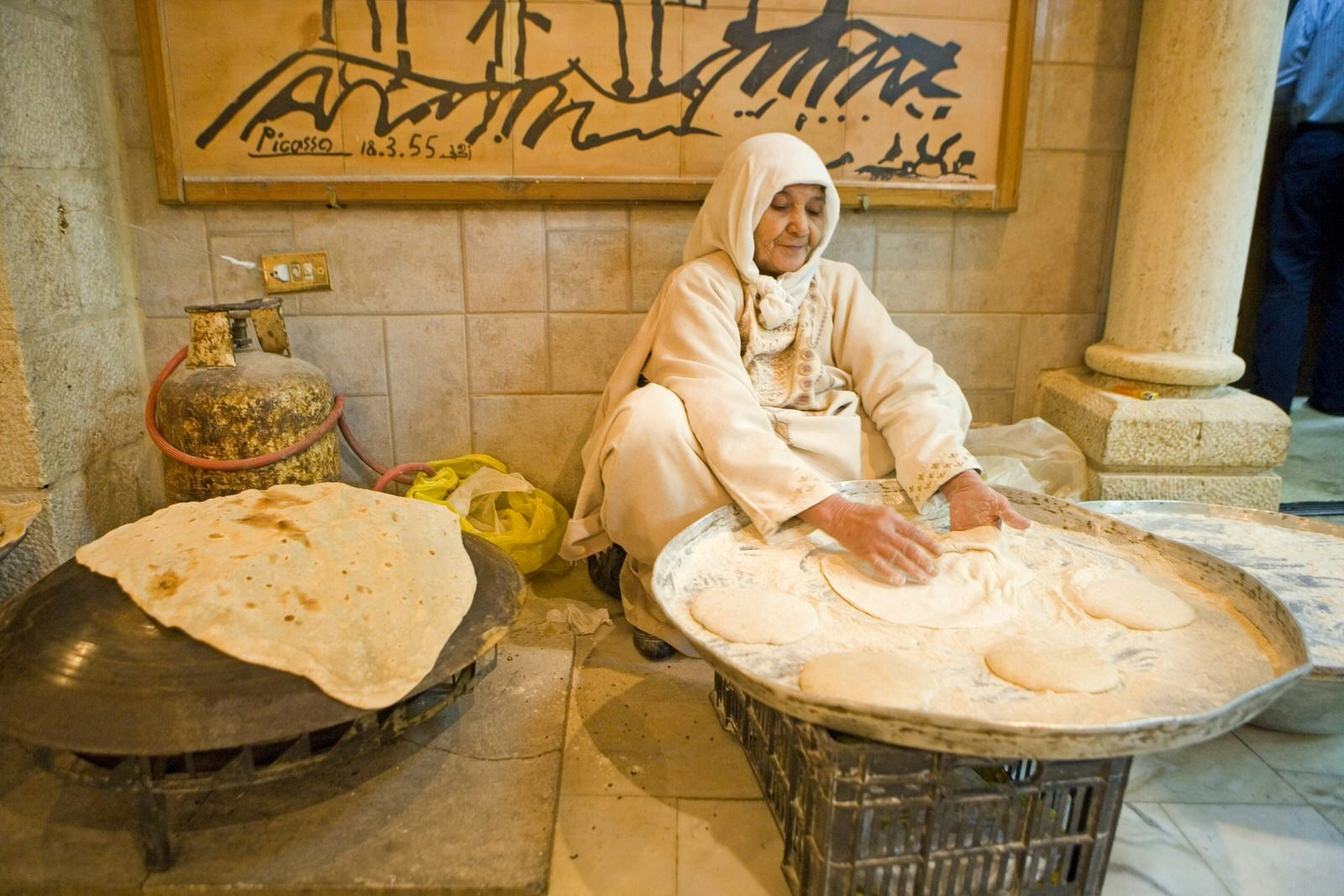 A woman shapes flatbread on a traditional tray at Tawaheen Al Hawa. Amman, Jordan © Sylvain Grandadam / Getty Images