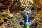 A waterfall in a canyon in Watkins Glen is illuminated by light from above © Ultima_Gaina / Getty Images