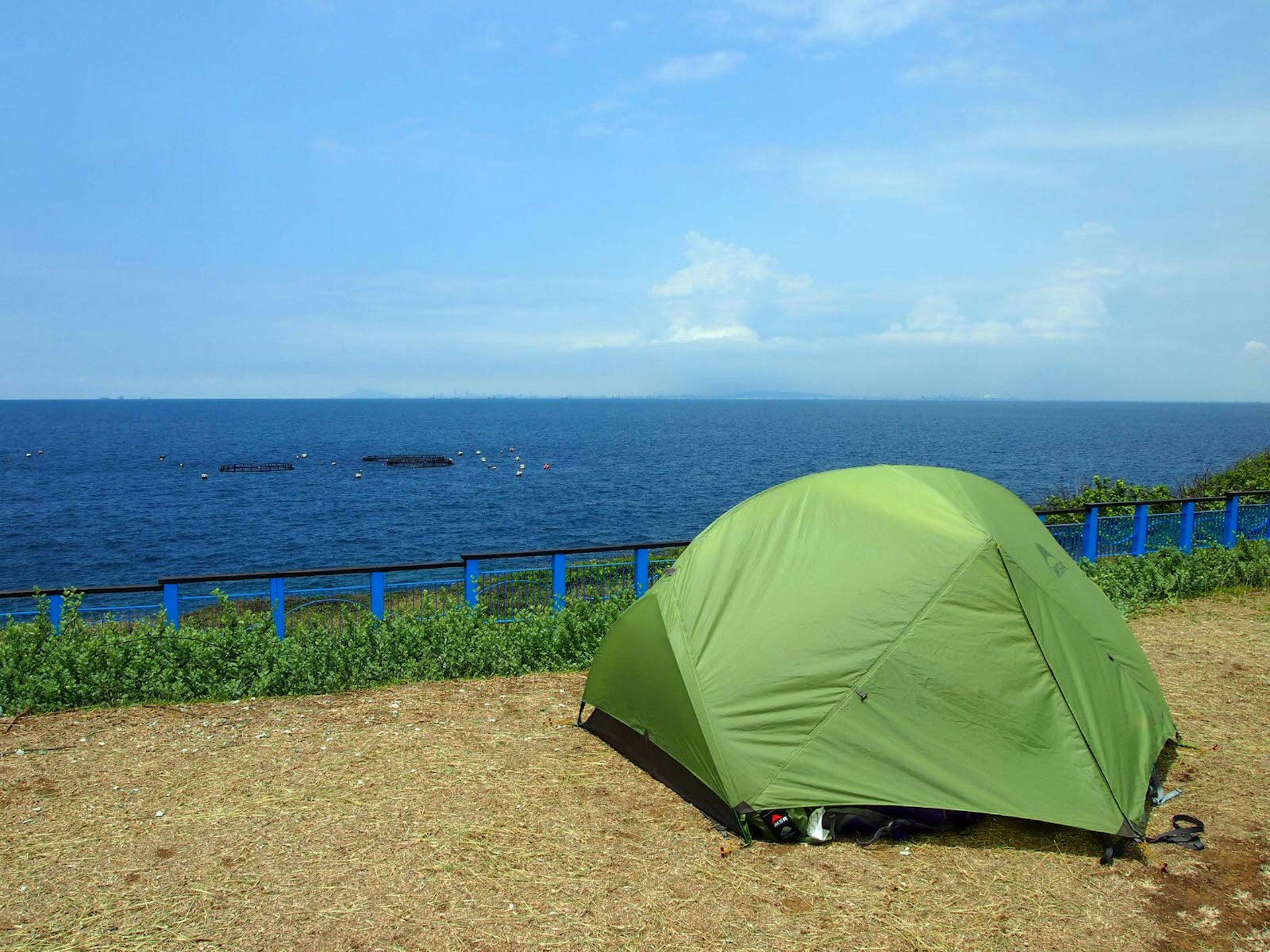 A green tent pitched on a patch of dirt overlooking the sea. Camping is popular on Little Liuchiu and offers amazing views © Tess Humphrys / Lonely Planet