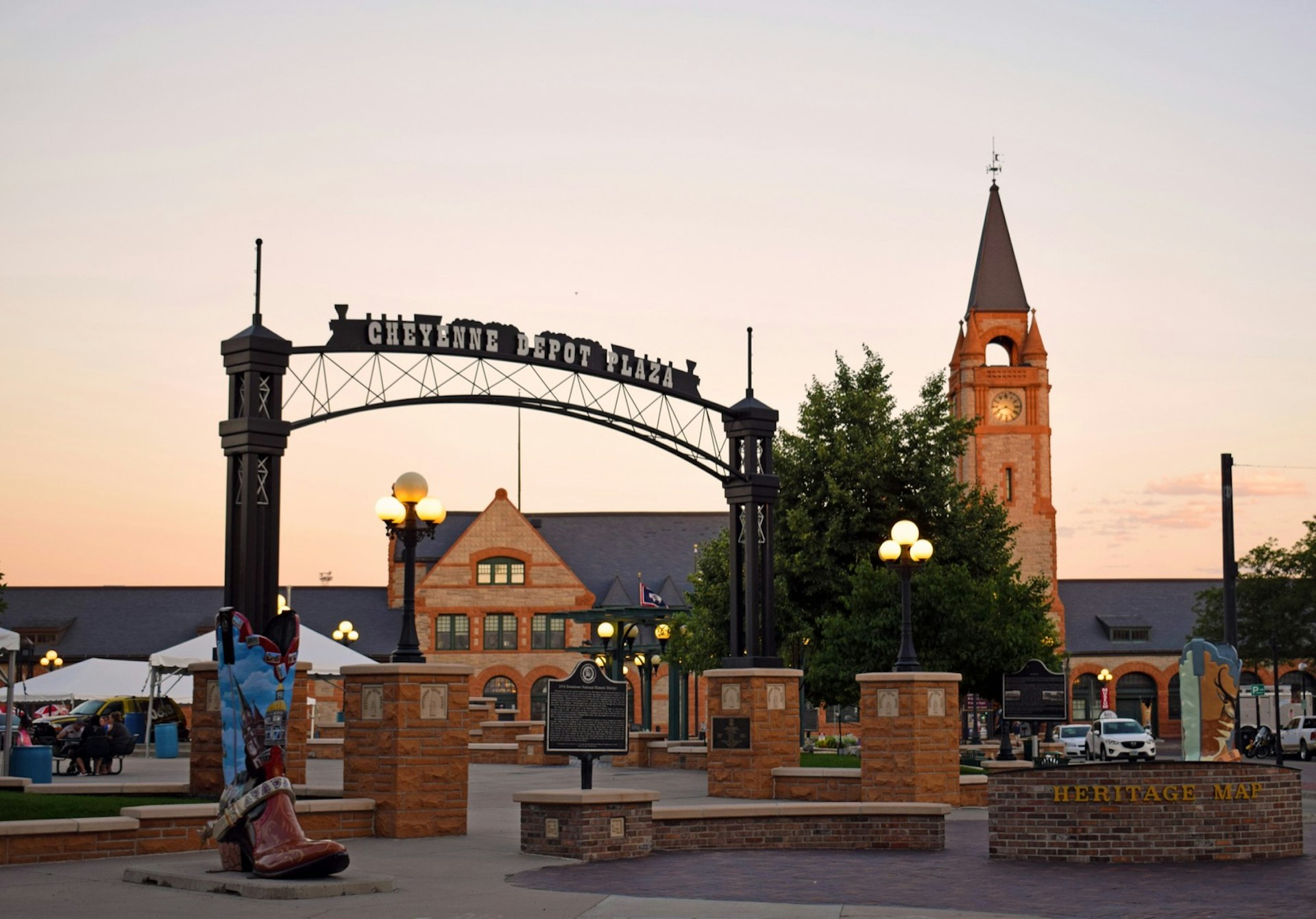 Buildings and a plaza glow in the warmth of a sunset, with a train-shaped sign and oversized cowboy-boot sculpture in Cheyenne, Wyoming © Dave Parfitt / Lonely Planet